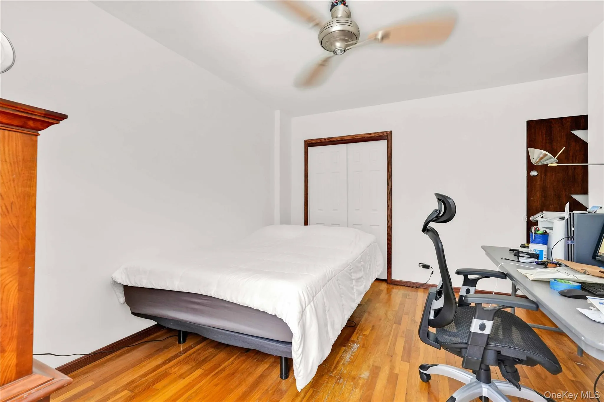 Bedroom featuring light wood finished floors, a ceiling fan, a closet, and an office area Bedroom featuring light wood finished floors, a ceiling fan, a closet, and an office area