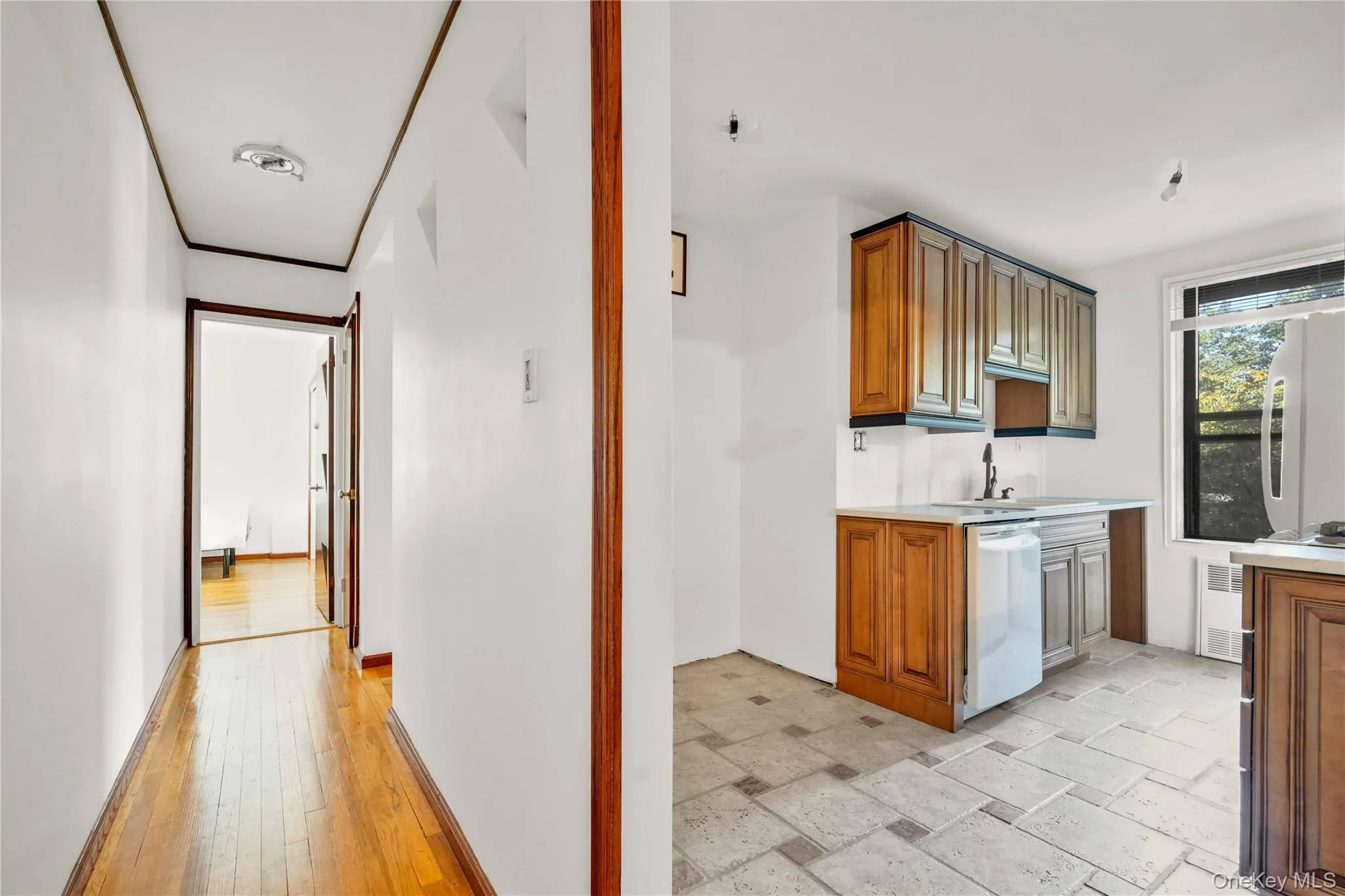 Kitchen with light countertops, brown cabinetry, fridge, white dishwasher, and stone tile floors Kitchen with light countertops, brown cabinetry, fridge, white dishwasher, and stone tile floors