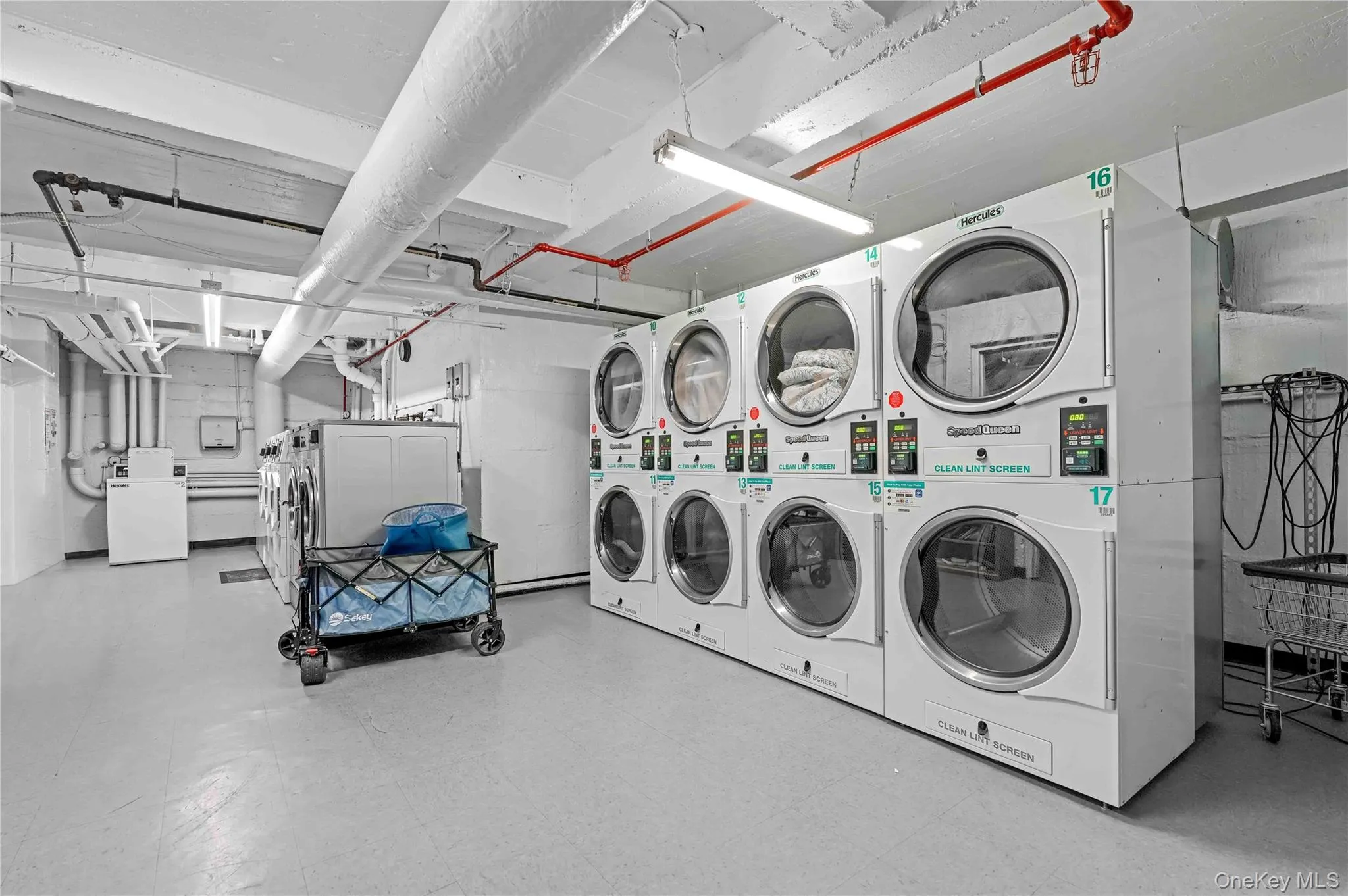 Shared laundry room featuring tile patterned floors, independent washer and dryer, and stacked washing machine and dryer Shared laundry room featuring tile patterned floors, independent washer and dryer, and stacked washing machine and dryer
