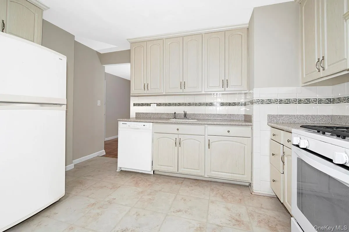 Kitchen with white appliances, backsplash, and light stone counters Kitchen with white appliances, backsplash, and light stone counters