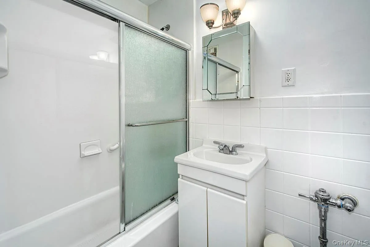 Full bath with combined bath / shower with glass door, tile walls, and vanity Full bath with combined bath / shower with glass door, tile walls, and vanity