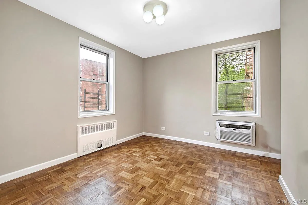 Empty room with radiator heating unit, healthy amount of natural light, and a wall mounted air conditioner Empty room with radiator heating unit, healthy amount of natural light, and a wall mounted air conditioner