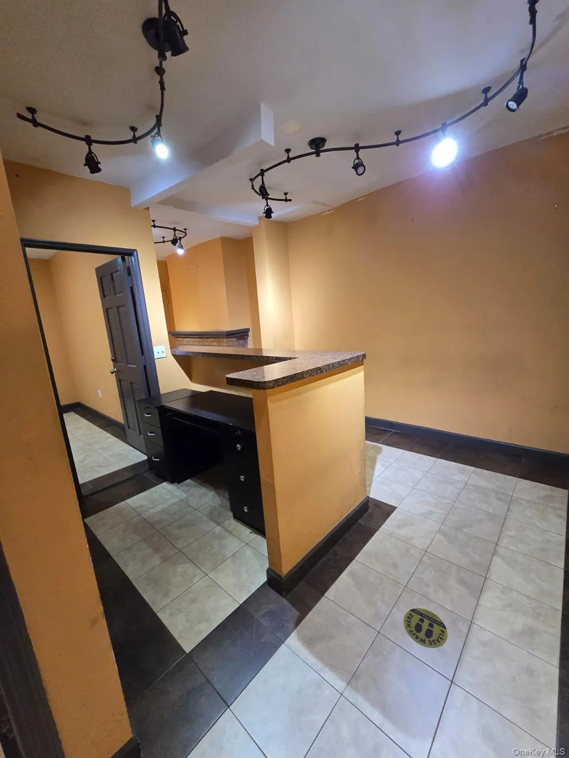 Kitchen featuring dark countertops, light tile patterned flooring, and rail lighting Kitchen featuring dark countertops, light tile patterned flooring, and rail lighting