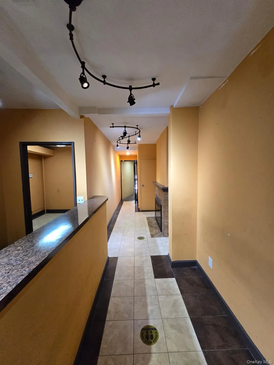 Hallway featuring dark tile patterned flooring and track lighting Hallway featuring dark tile patterned flooring and track lighting