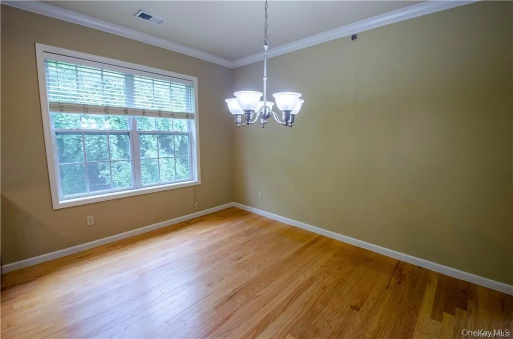 Unfurnished dining area featuring ornamental molding, a chandelier, and light wood-style flooring Unfurnished dining area featuring ornamental molding, a chandelier, and light wood-style flooring