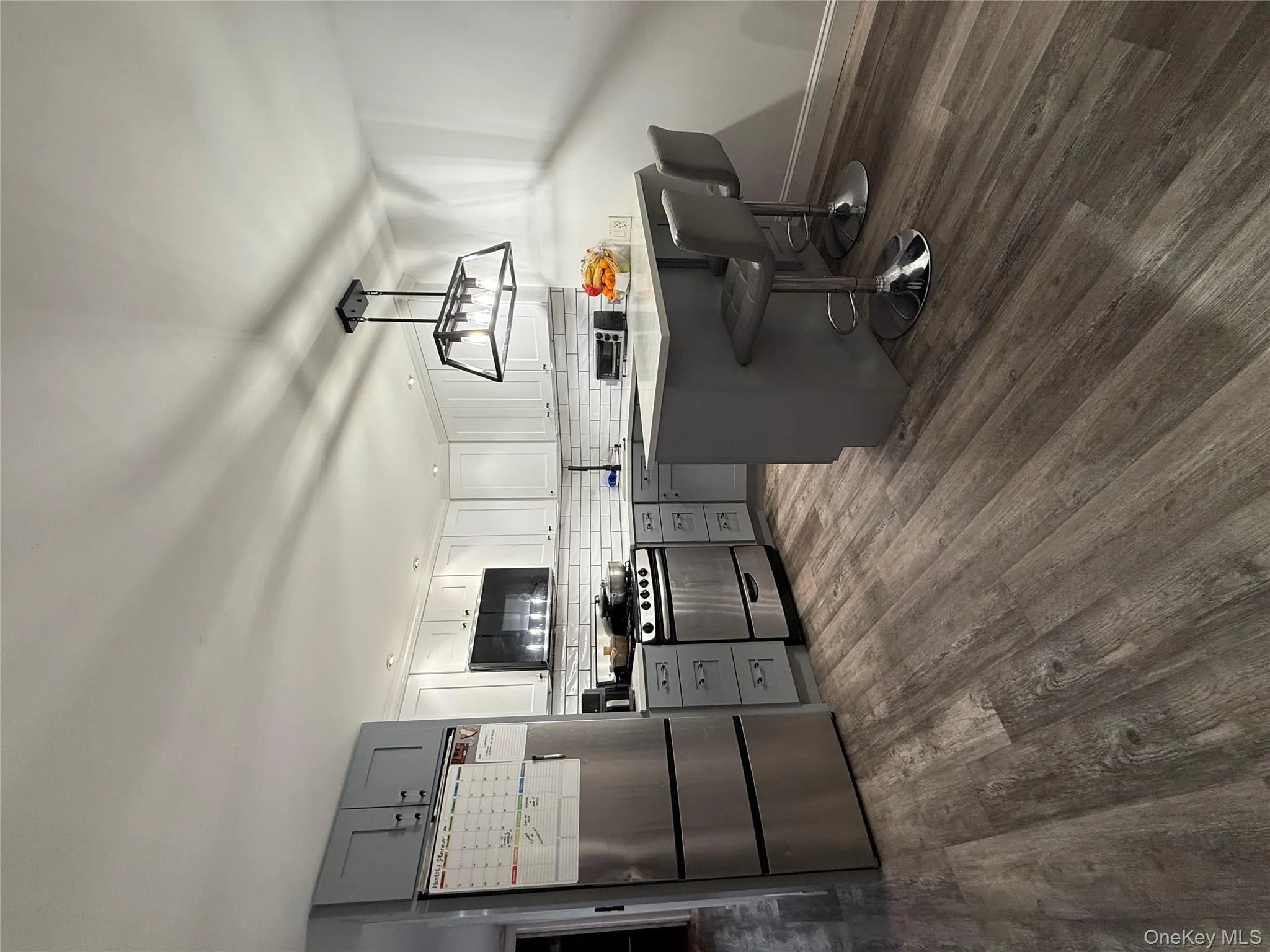 Kitchen featuring gray cabinets, refrigerator, light countertops, tasteful backsplash, and a breakfast bar area Kitchen featuring gray cabinets, refrigerator, light countertops, tasteful backsplash, and a breakfast bar area