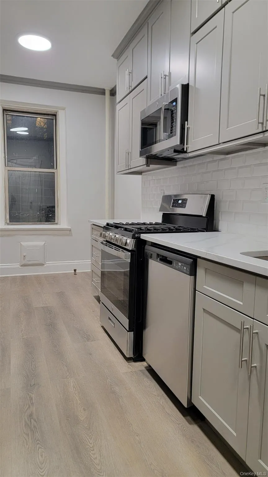 Kitchen with stainless steel appliances, light wood-type flooring, tasteful backsplash, light stone counters, and recessed lighting Kitchen with stainless steel appliances, light wood-type flooring, tasteful backsplash, light stone counters, and recessed lighting