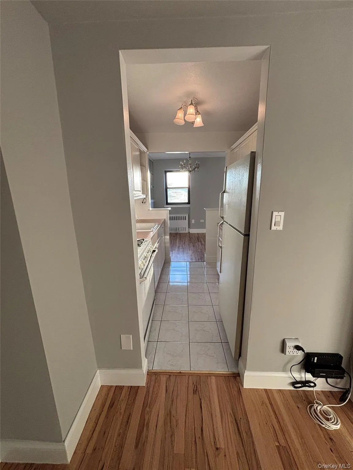 Kitchen with white cabinets, a chandelier, light wood finished floors, light countertops, and white appliances Kitchen with white cabinets, a chandelier, light wood finished floors, light countertops, and white appliances