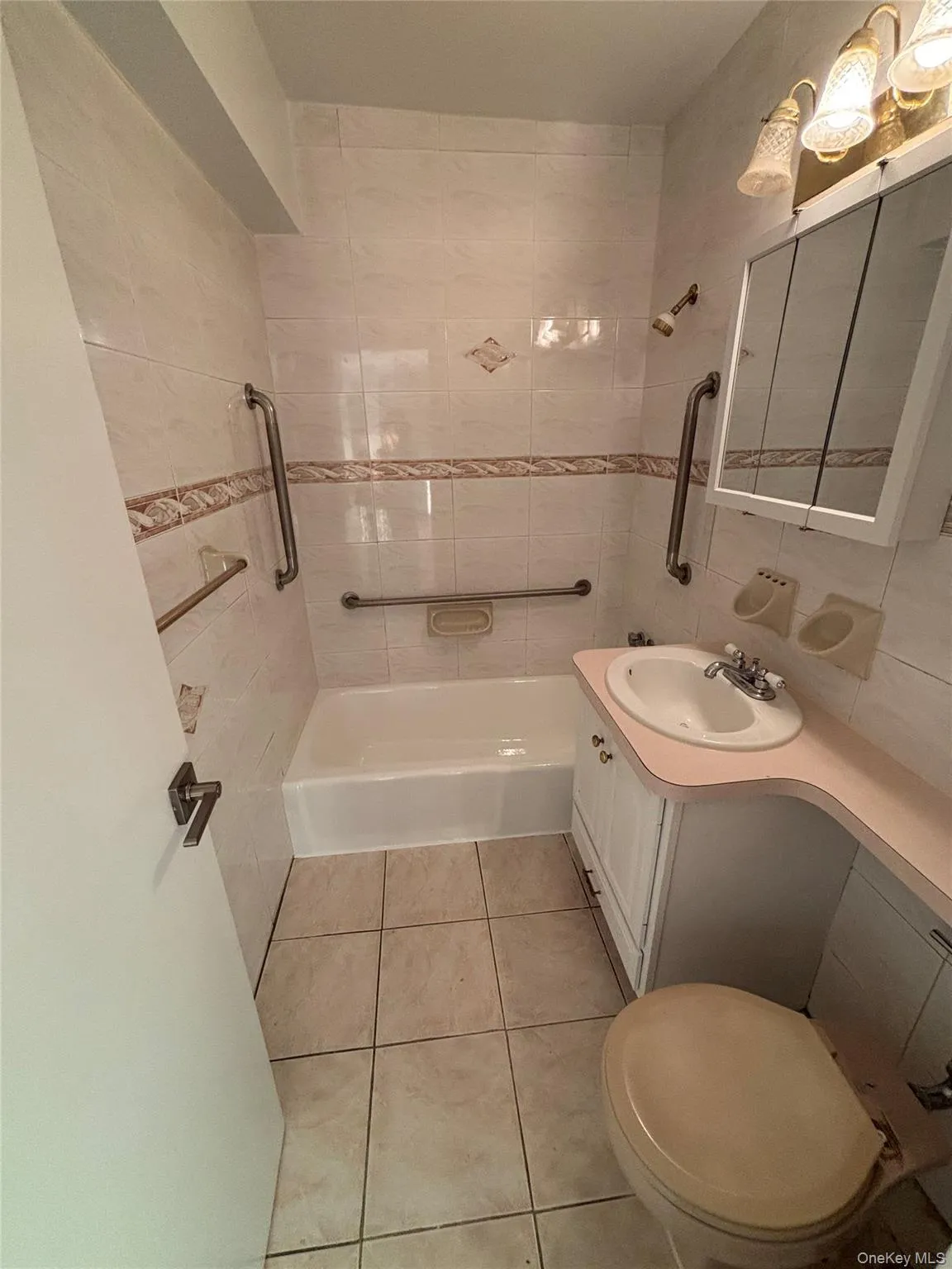 Full bath with bathtub / shower combination, vanity, tile walls, and light tile patterned floors Full bath with bathtub / shower combination, vanity, tile walls, and light tile patterned floors