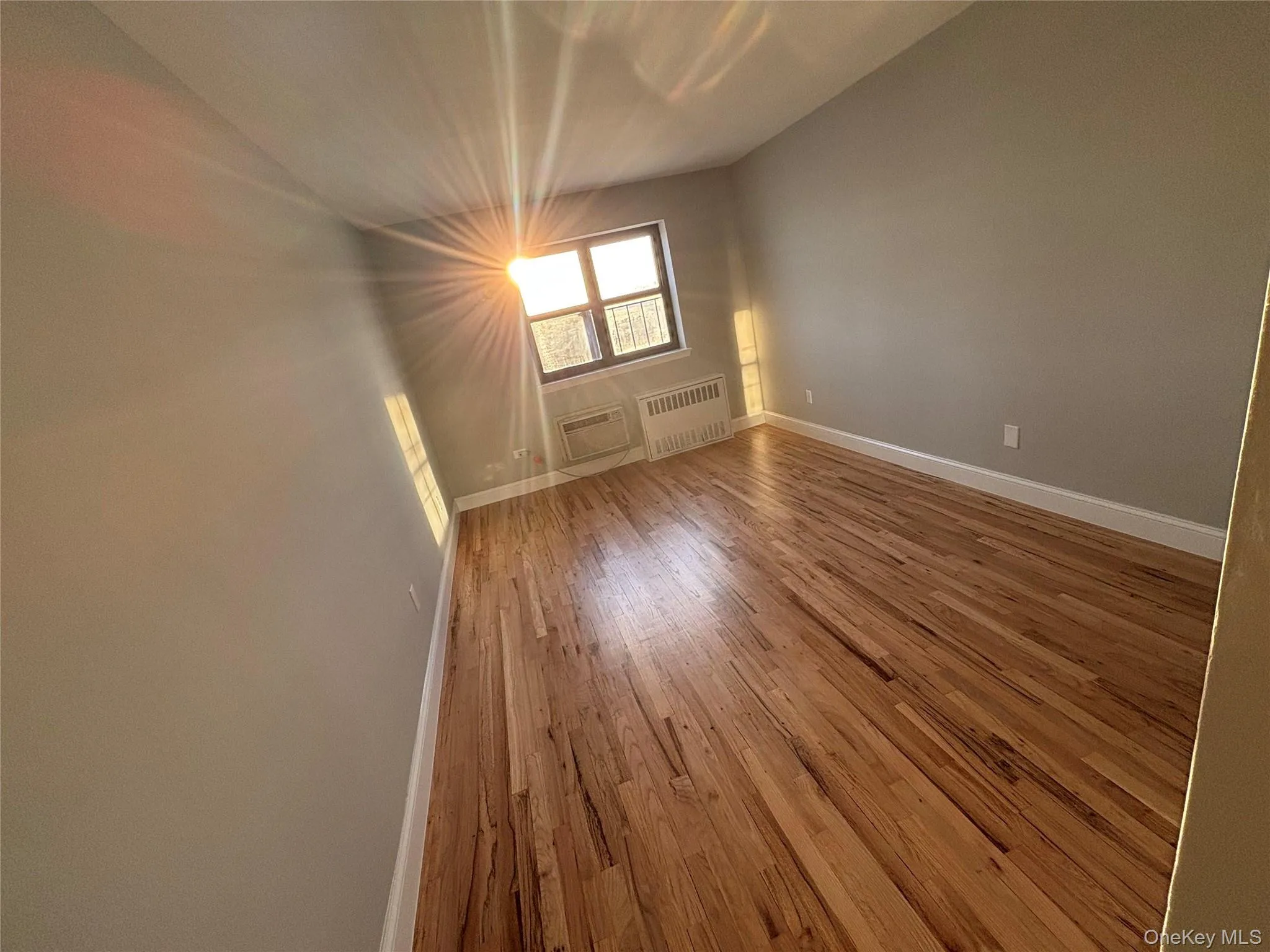 Empty room with hardwood / wood-style flooring and radiator Empty room with hardwood / wood-style flooring and radiator