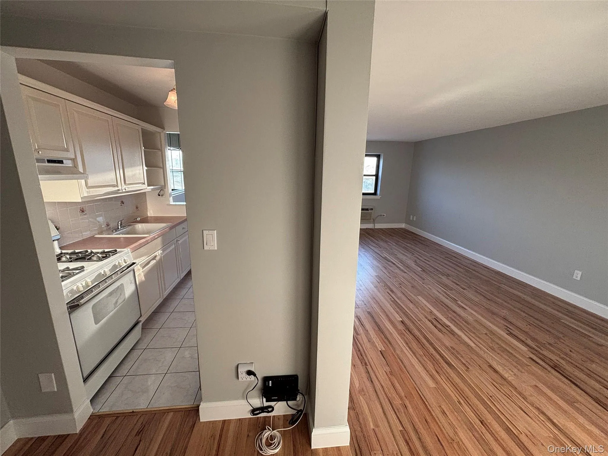 Kitchen featuring white range with gas stovetop, white cabinetry, light wood-type flooring, light countertops, and tasteful backsplash Kitchen featuring white range with gas stovetop, white cabinetry, light wood-type flooring, light countertops, and tasteful backsplash