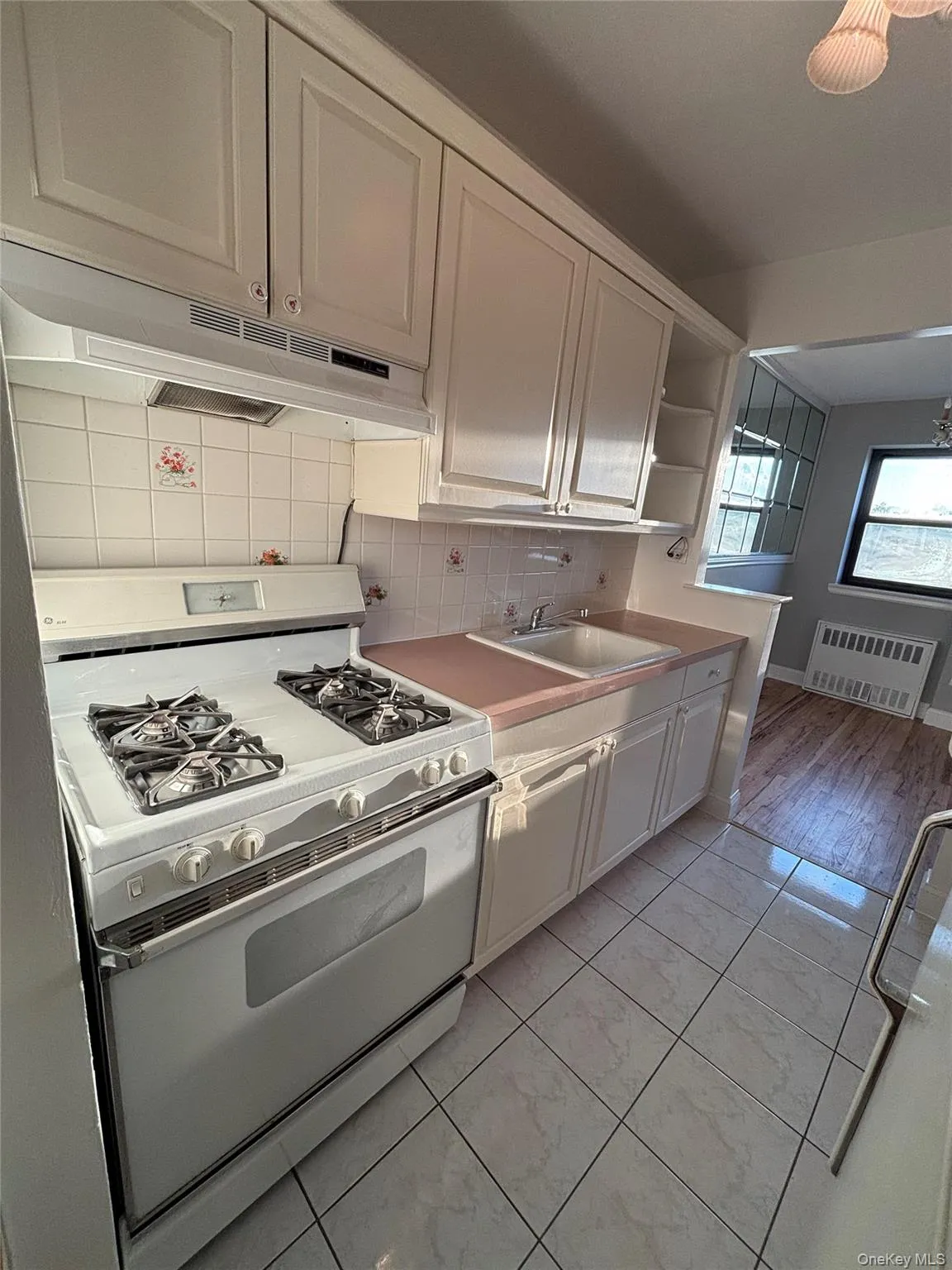 Kitchen featuring gas range gas stove, tasteful backsplash, under cabinet range hood, white cabinets, and open shelves Kitchen featuring gas range gas stove, tasteful backsplash, under cabinet range hood, white cabinets, and open shelves