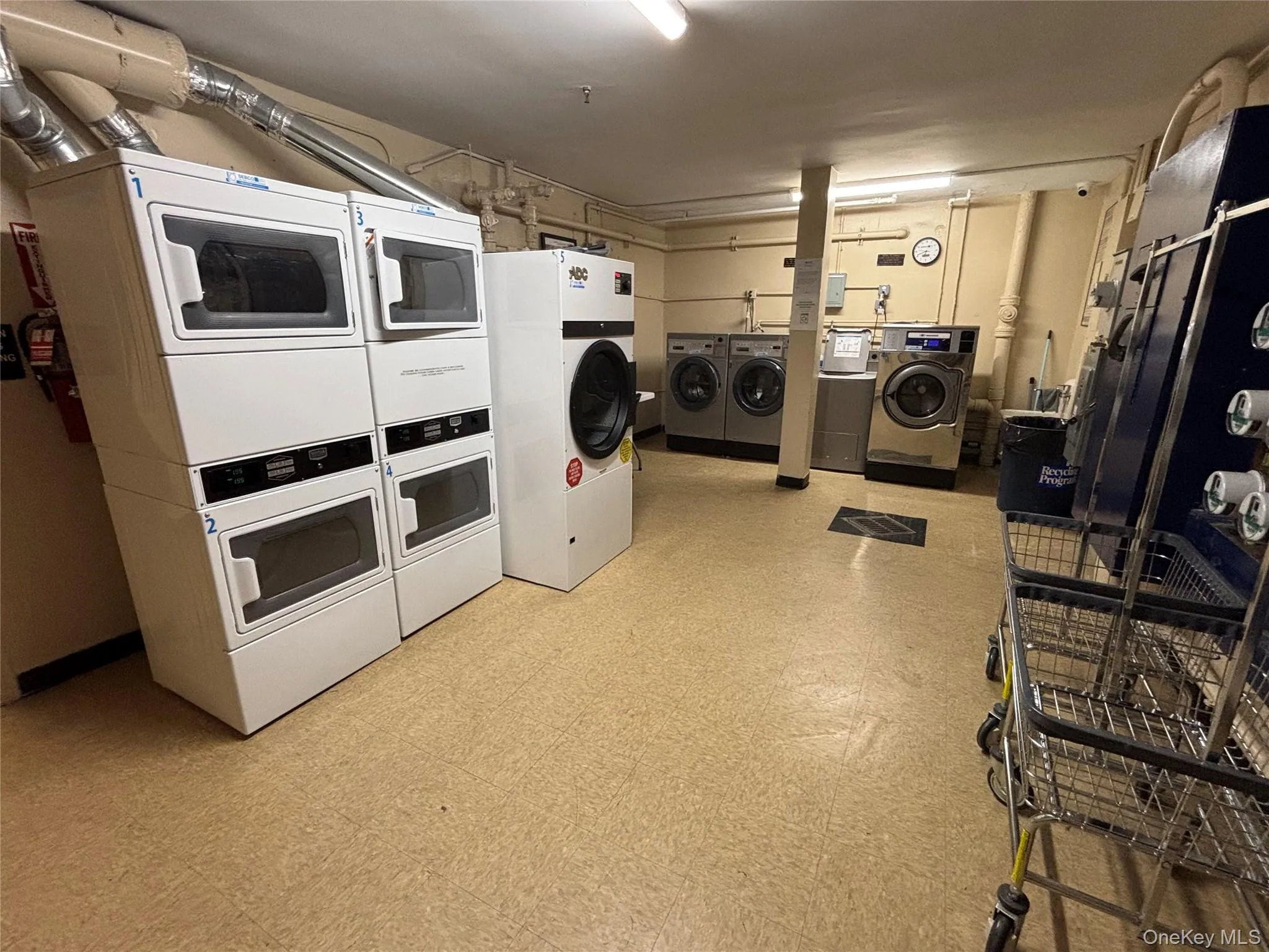 Communal laundry room with light floors, estacked washer and dryer, and washing machine and clothes dryer Communal laundry room with light floors, estacked washer and dryer, and washing machine and clothes dryer