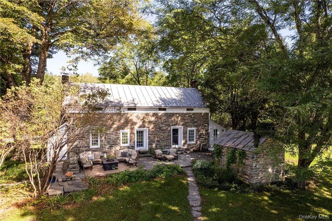 View of front of stone house with an outdoor living space, a patio area, and yard. View of front of stone house with an outdoor living space, a patio area, and yard.