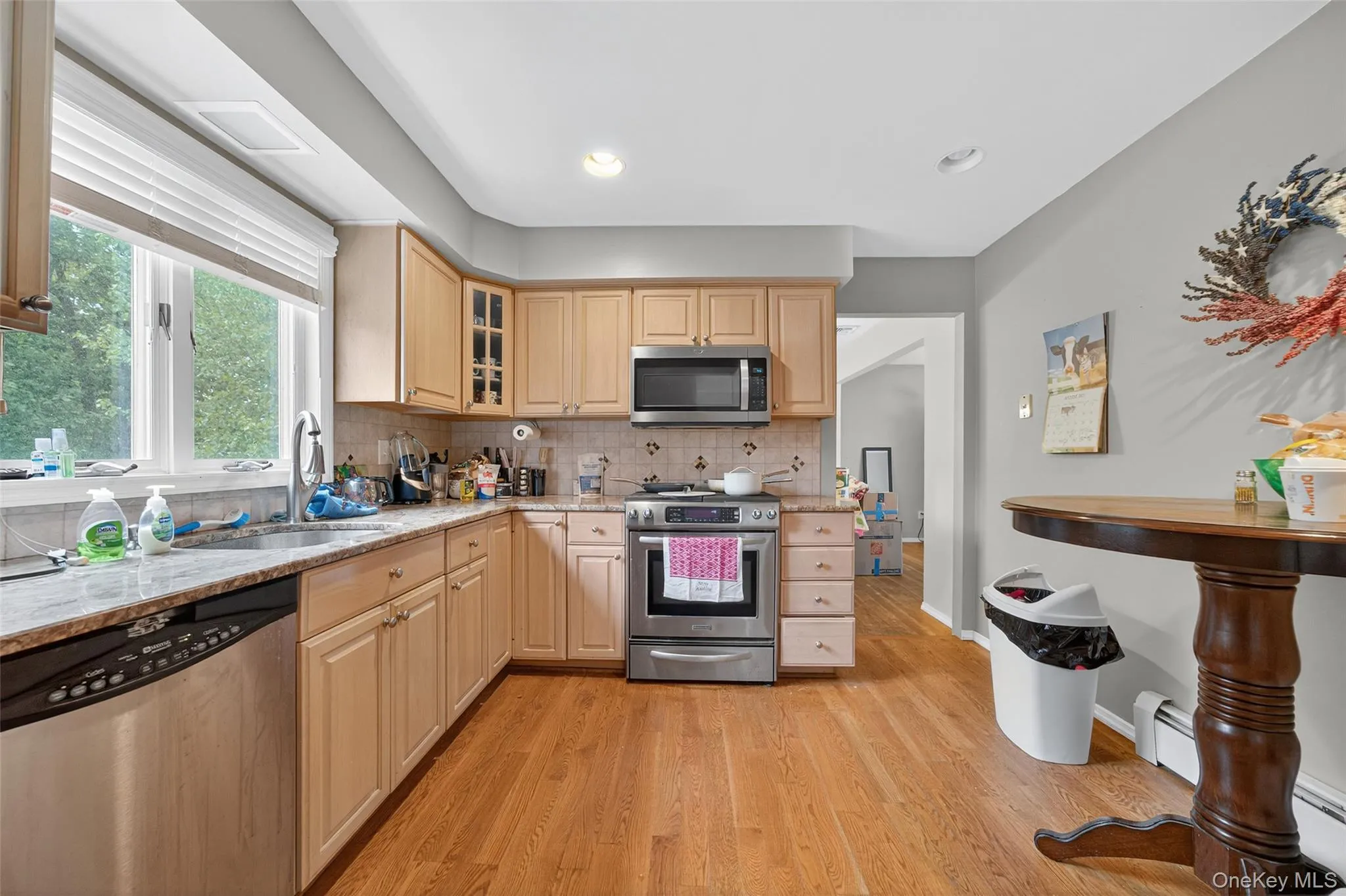 Kitchen with appliances with stainless steel finishes, decorative backsplash, light wood-style flooring, light brown cabinetry, and recessed lighting Kitchen with appliances with stainless steel finishes, decorative backsplash, light wood-style flooring, light brown cabinetry, and recessed lighting