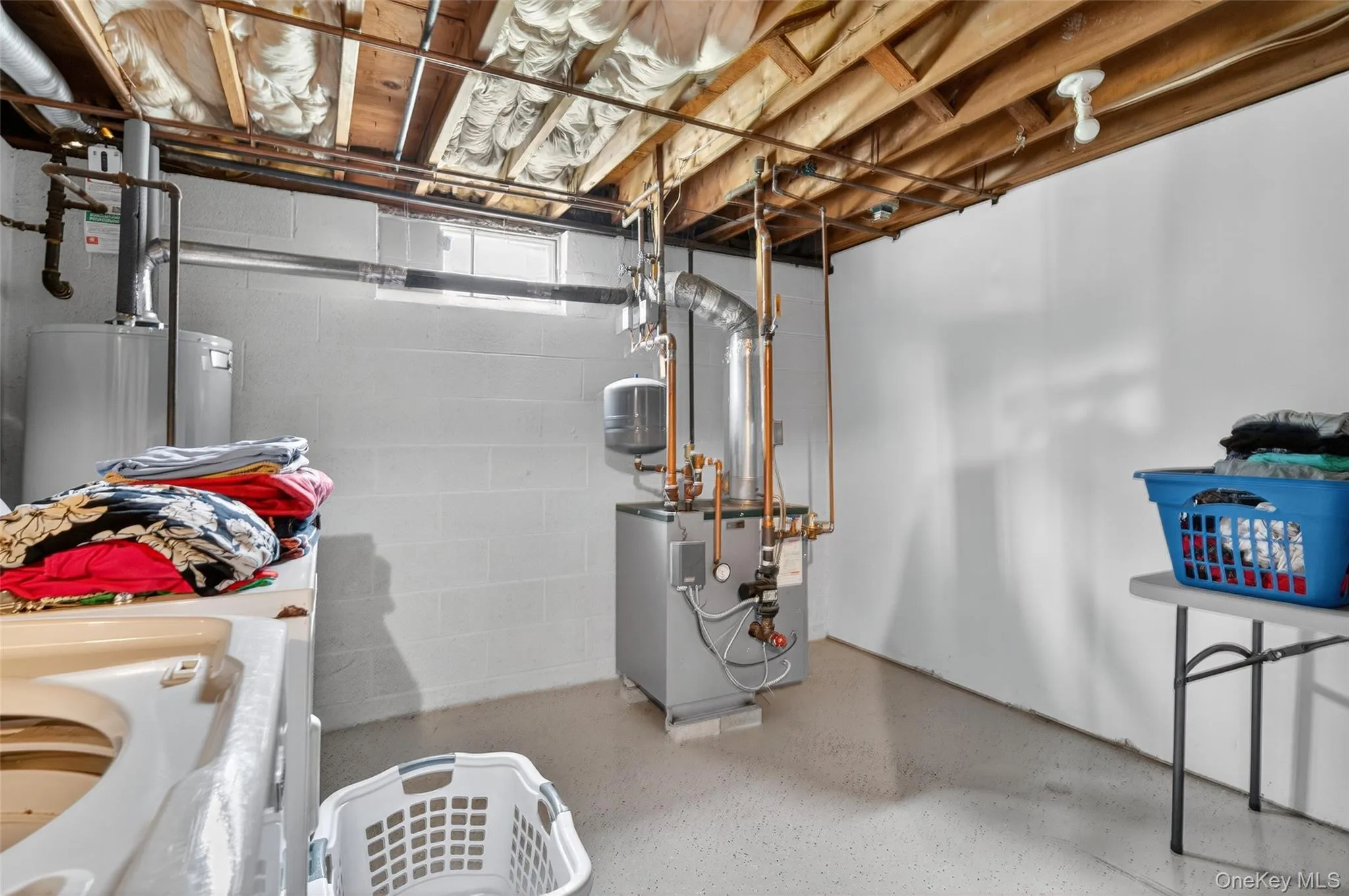 Unfinished below grade area with a heating unit and water heater Unfinished below grade area with a heating unit and water heater