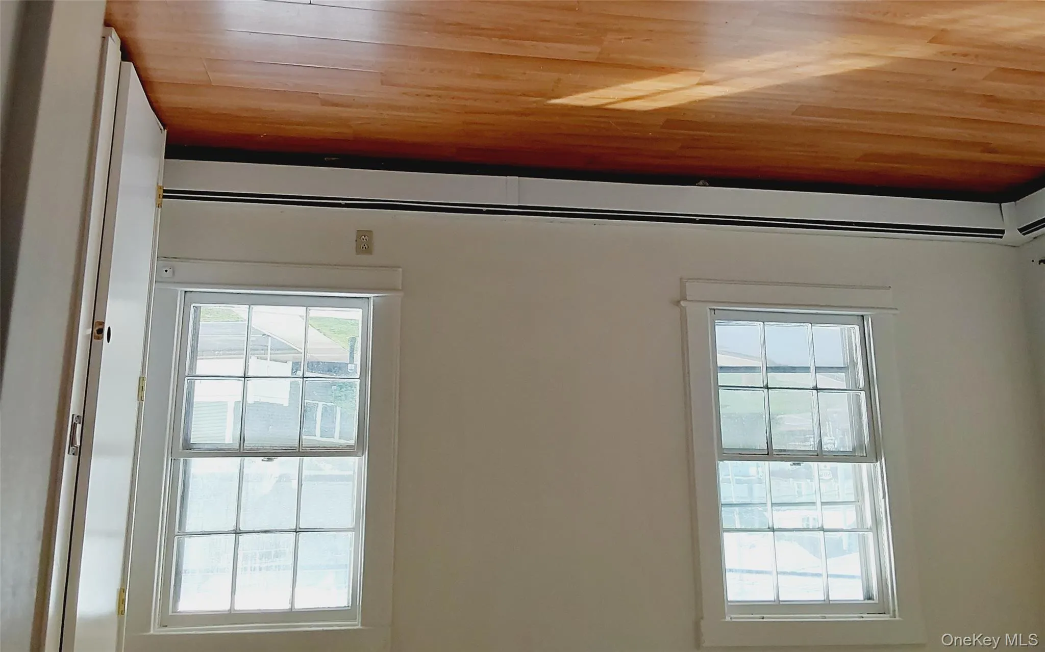 Spare room featuring baseboard heating, light wood-style floors, and plenty of natural light Spare room featuring baseboard heating, light wood-style floors, and plenty of natural light