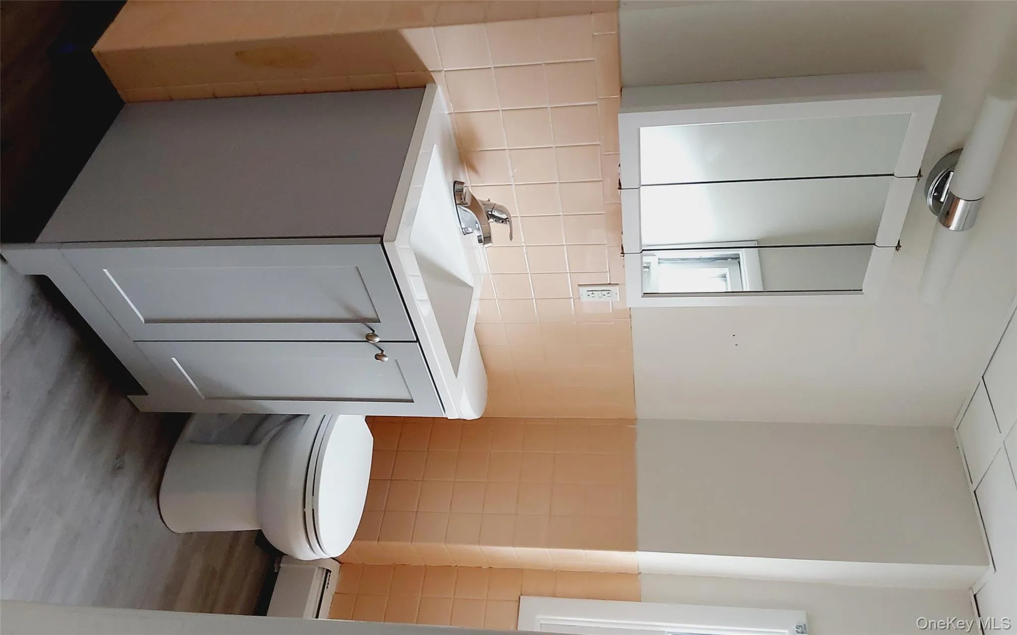 Half bathroom with vanity, wood finished floors, tile walls, baseboard heating, and wainscoting Half bathroom with vanity, wood finished floors, tile walls, baseboard heating, and wainscoting