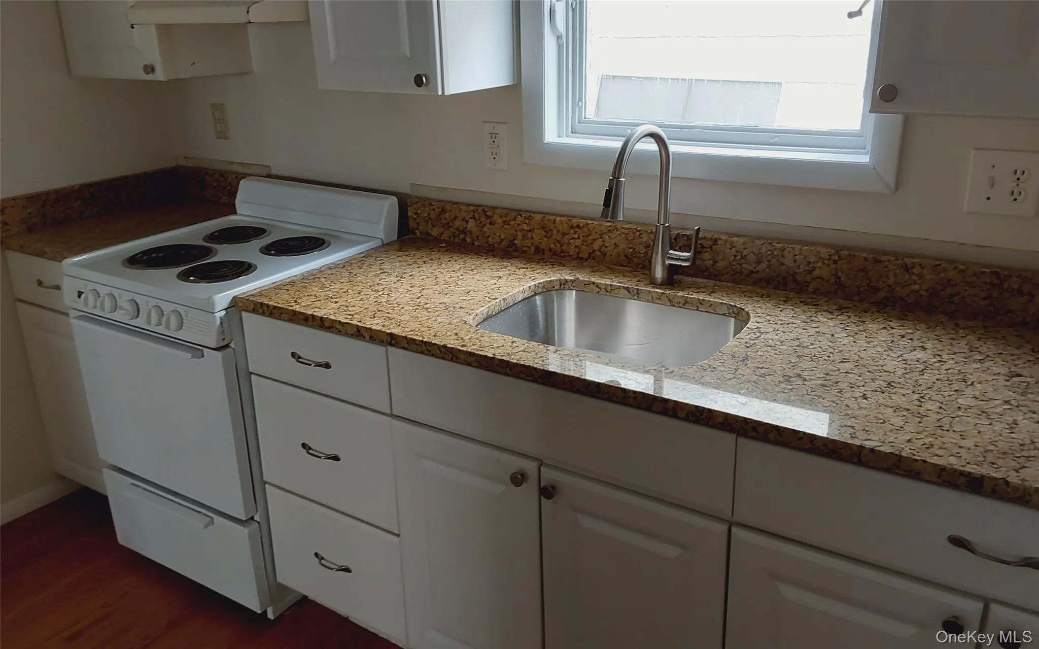 Kitchen featuring white range with electric stovetop, white cabinets, light stone countertops, range hood, and wood finished floors Kitchen featuring white range with electric stovetop, white cabinets, light stone countertops, range hood, and wood finished floors