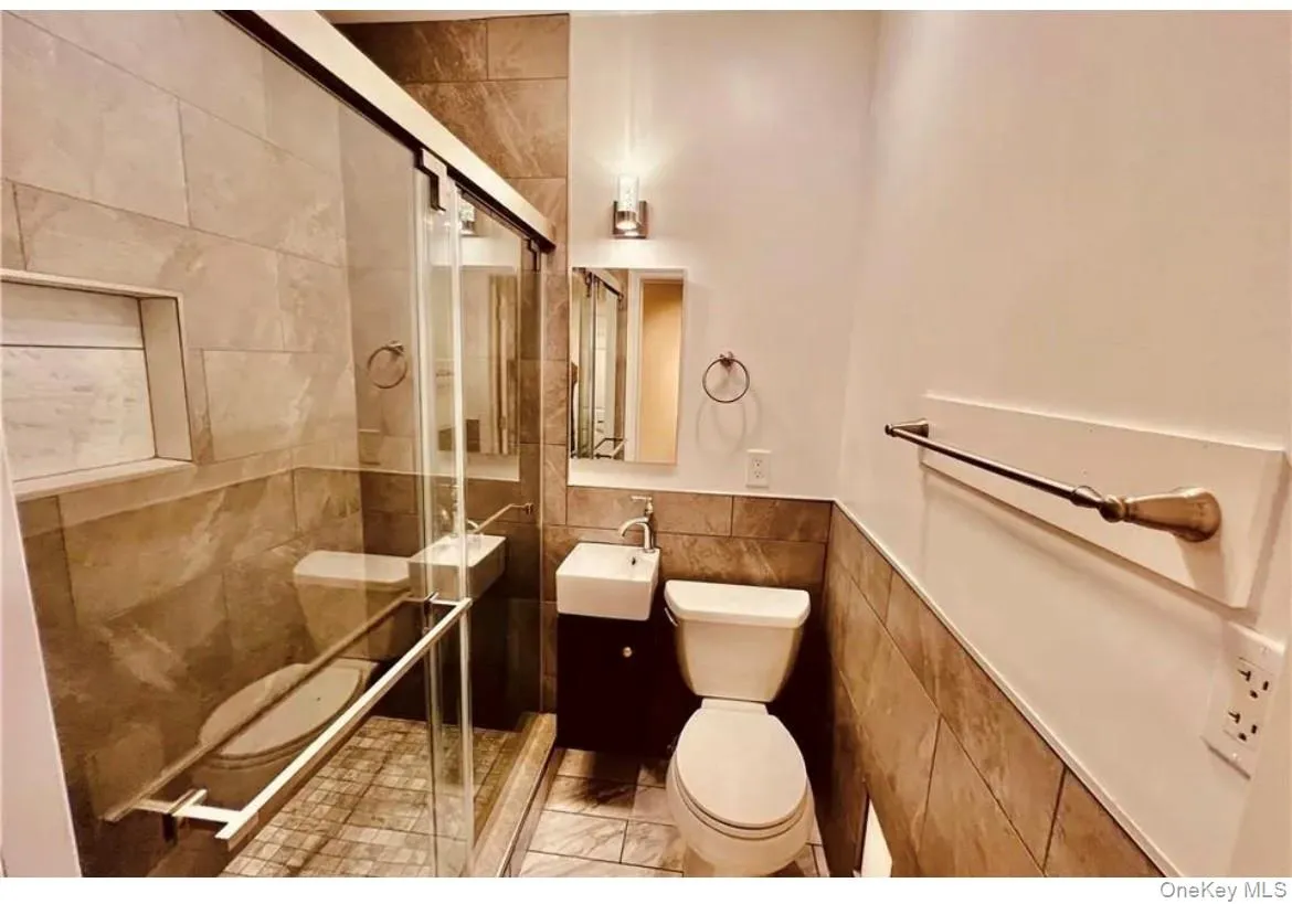 Full bathroom with a stall shower, tile walls, and vanity Full bathroom with a stall shower, tile walls, and vanity