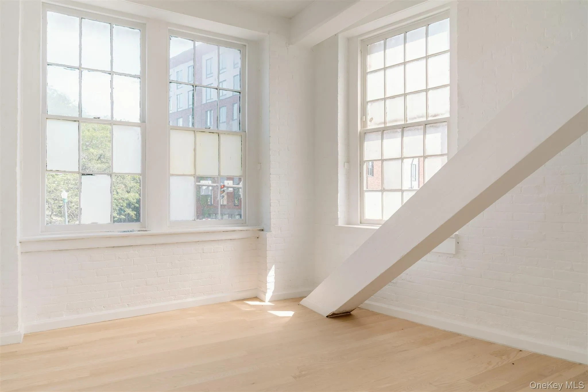 Spare room featuring brick wall and wood finished floors Spare room featuring brick wall and wood finished floors