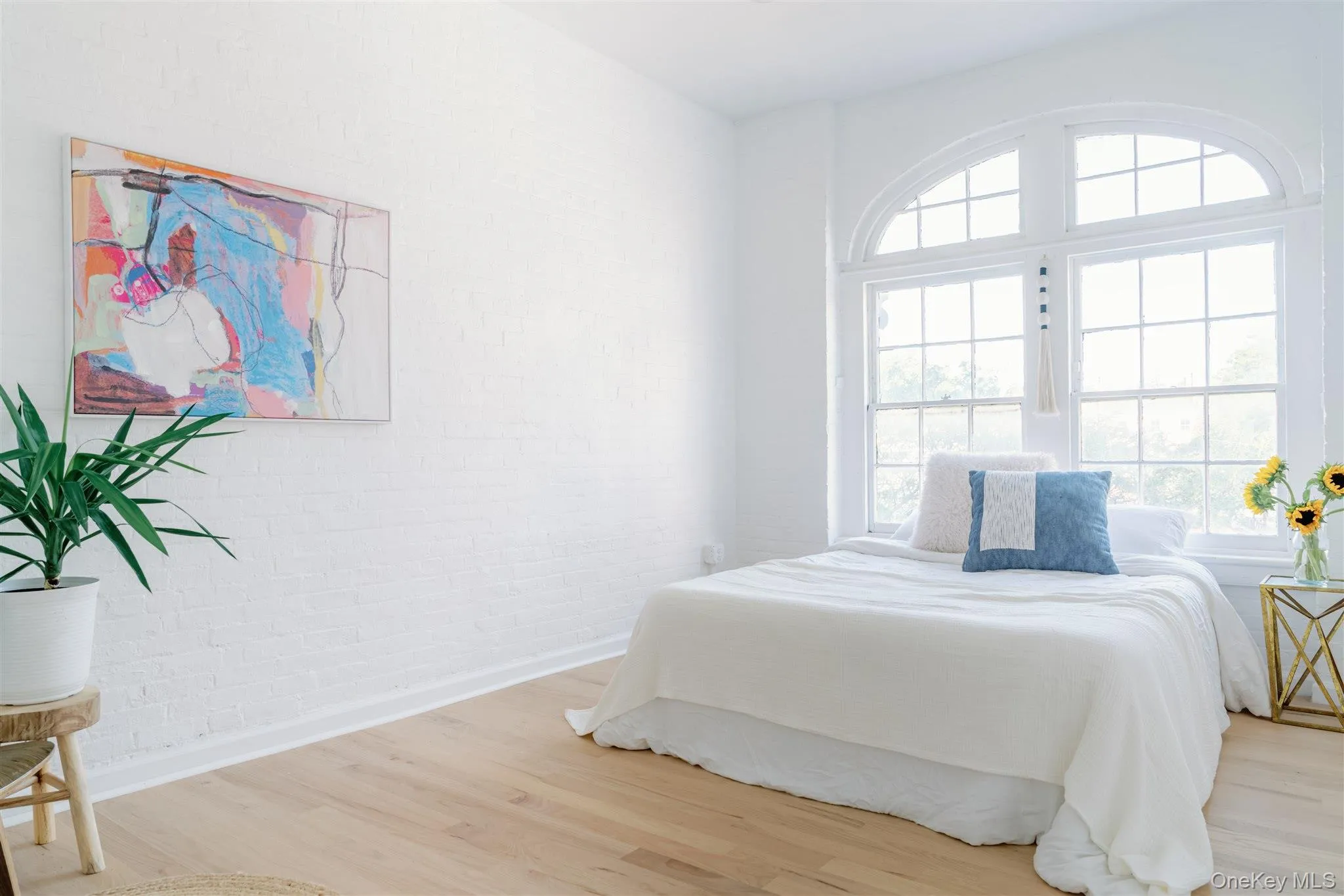 Bedroom with wood finished floors and brick wall Bedroom with wood finished floors and brick wall