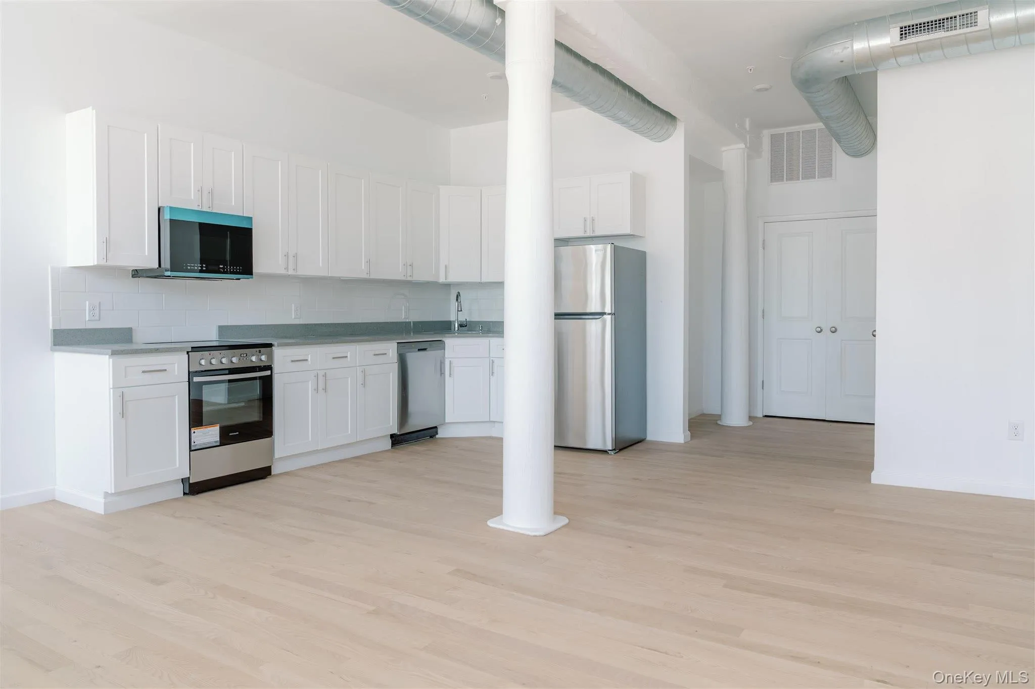Kitchen with white cabinetry, stainless steel appliances, decorative backsplash, and light wood-type flooring Kitchen with white cabinetry, stainless steel appliances, decorative backsplash, and light wood-type flooring