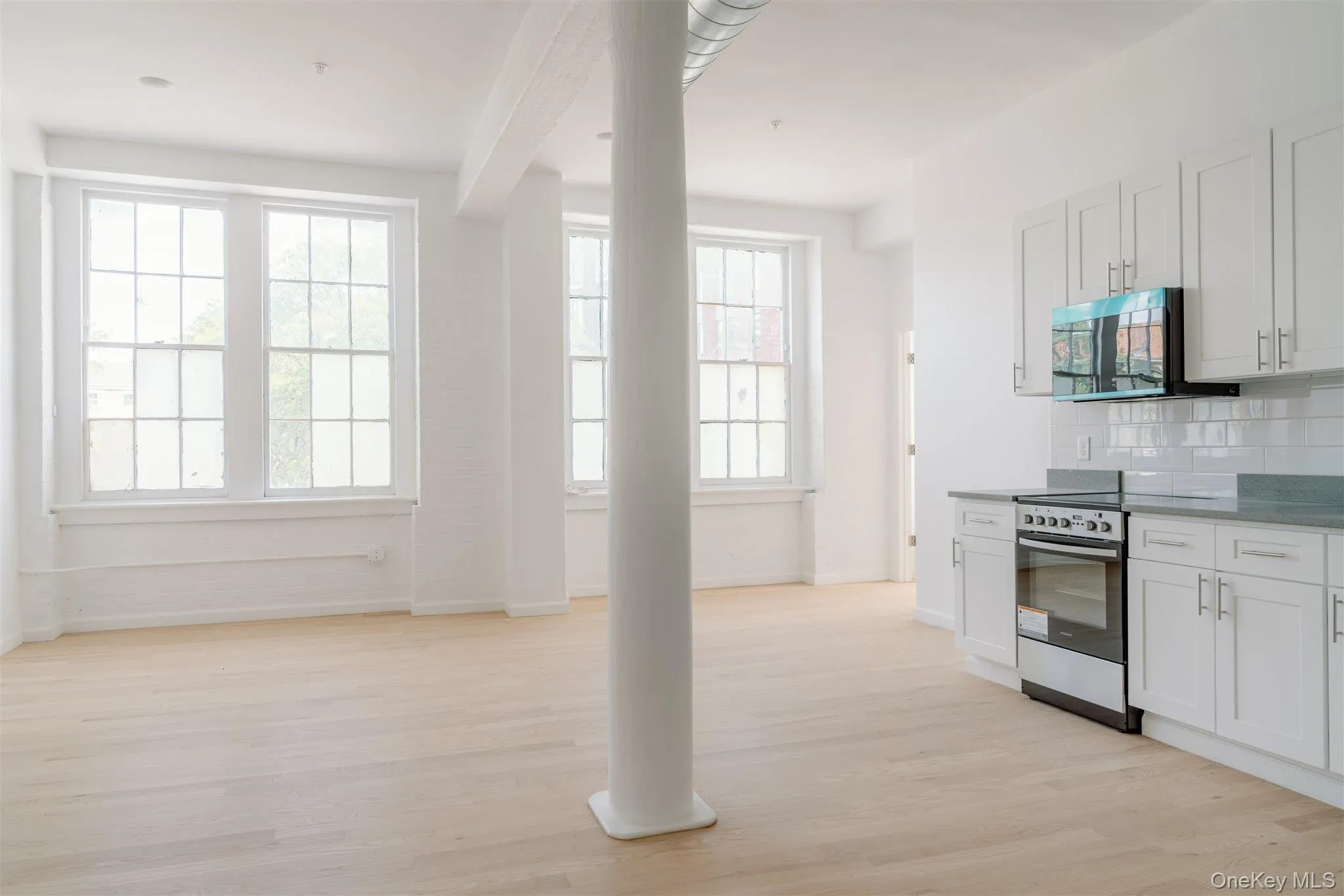 Kitchen featuring light wood-style flooring, decorative backsplash, white cabinetry, appliances with stainless steel finishes, and beamed ceiling Kitchen featuring light wood-style flooring, decorative backsplash, white cabinetry, appliances with stainless steel finishes, and beamed ceiling