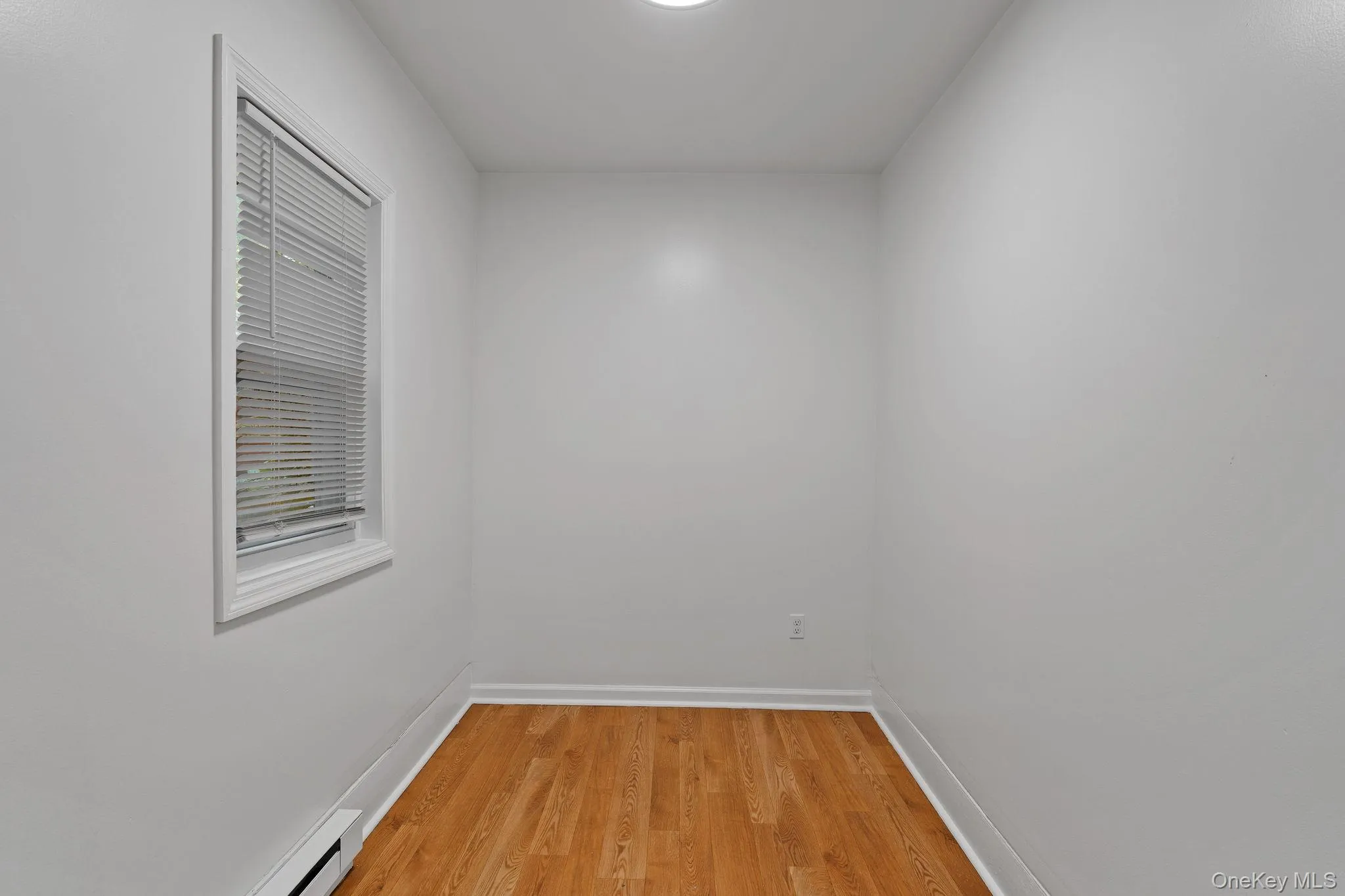 Unfurnished room with light wood-style floors and a baseboard radiator Unfurnished room with light wood-style floors and a baseboard radiator