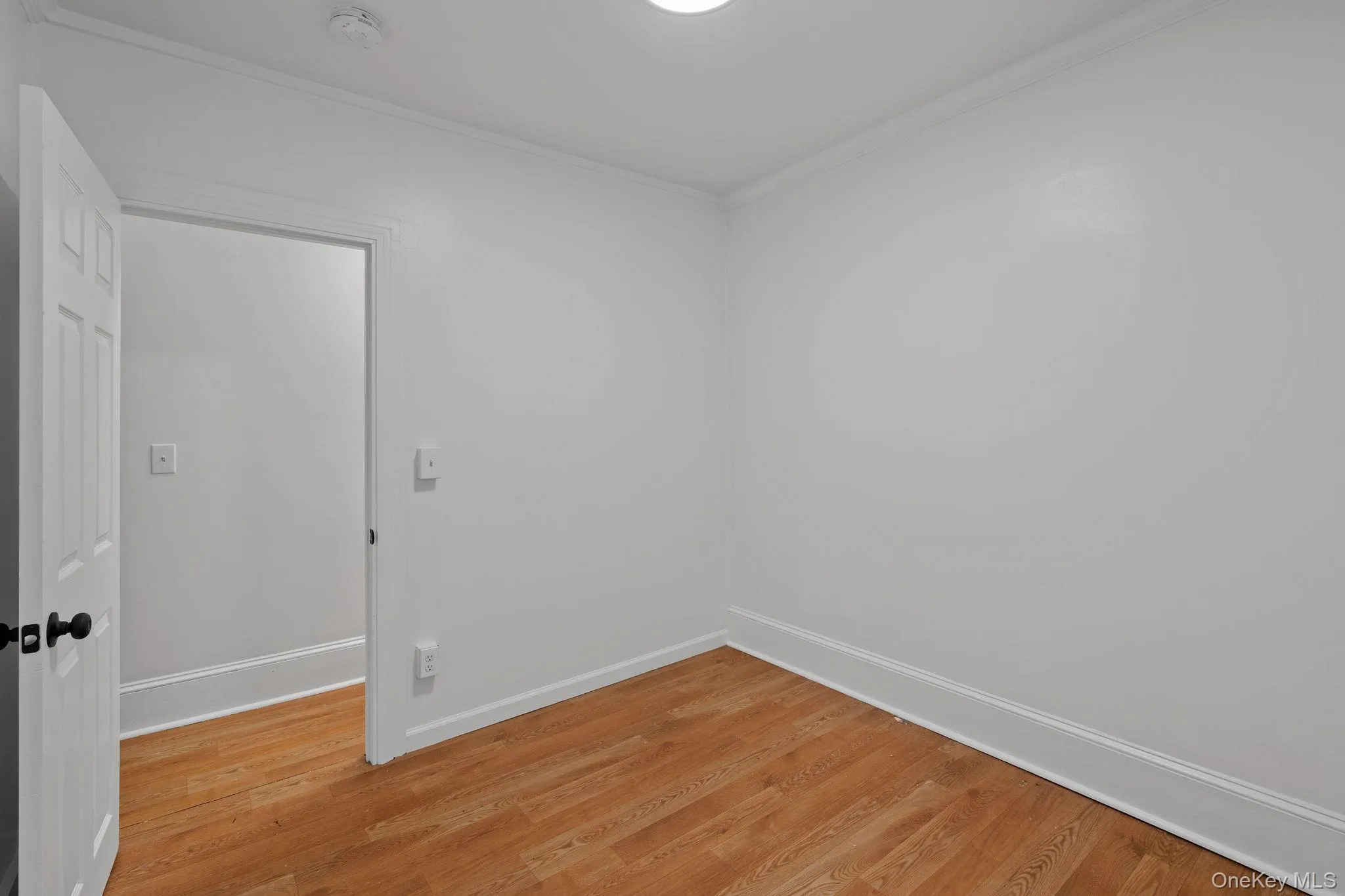 Unfurnished room with wood finished floors and crown molding Unfurnished room with wood finished floors and crown molding