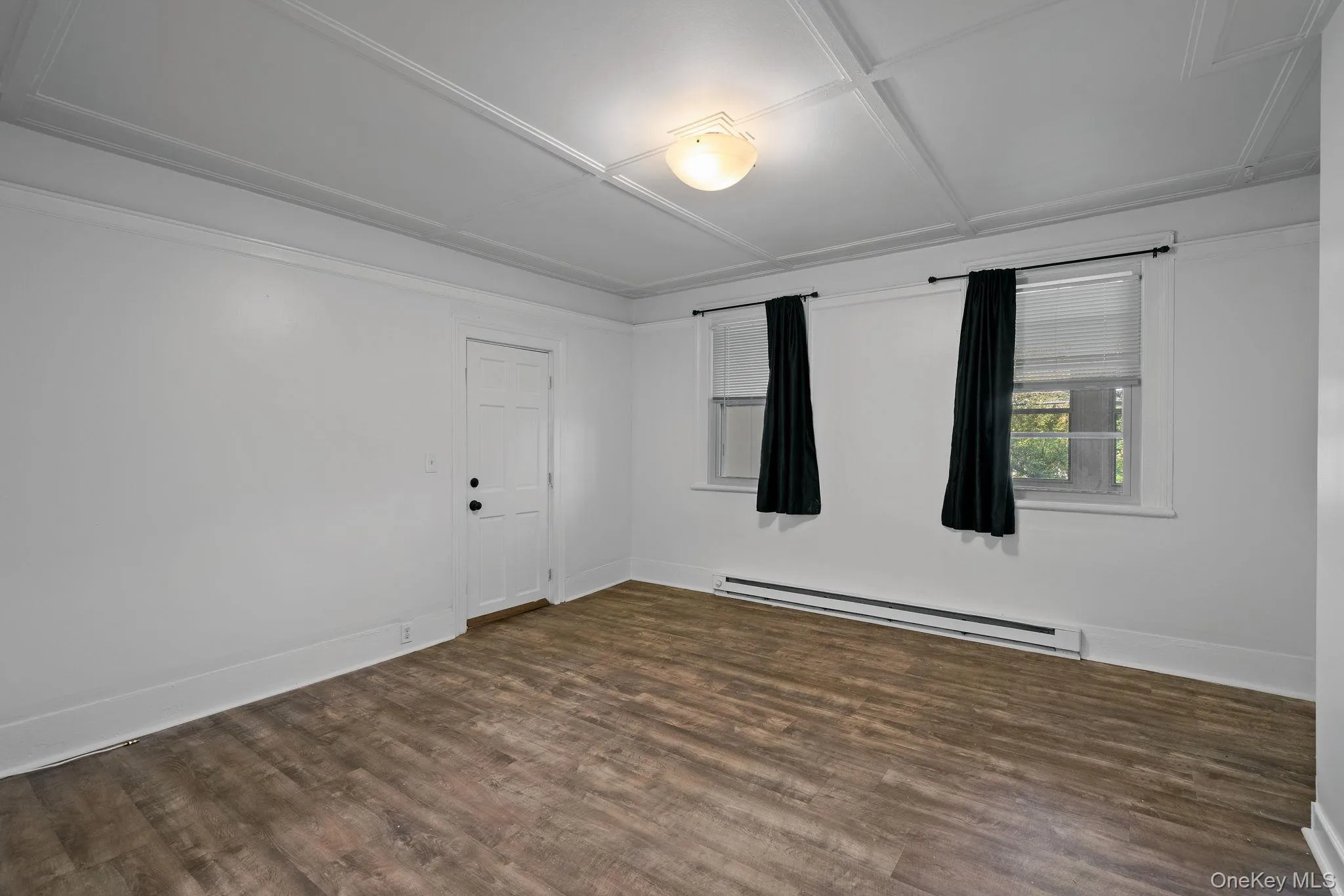 Unfurnished room featuring a baseboard radiator and dark wood-style flooring Unfurnished room featuring a baseboard radiator and dark wood-style flooring