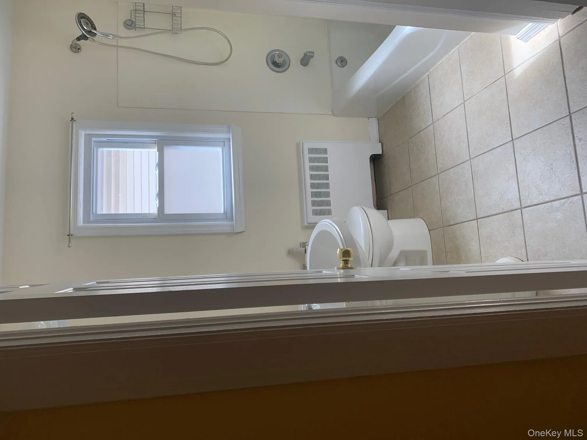 Full bath with light tile patterned floors, radiator heating unit, and washtub / shower combination Full bath with light tile patterned floors, radiator heating unit, and washtub / shower combination