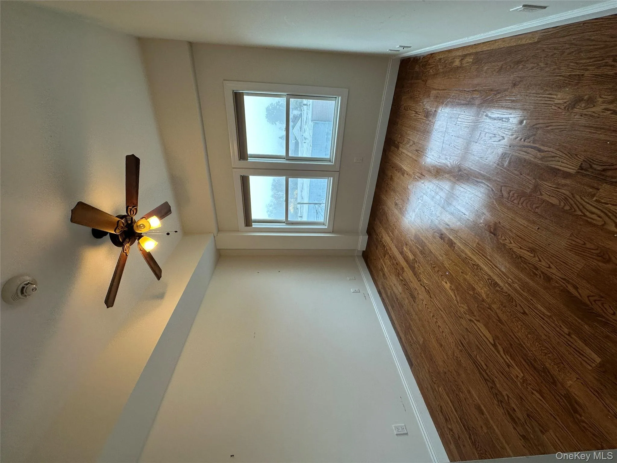 Spare room with dark wood-style floors, ceiling fan, and a smoke detector Spare room with dark wood-style floors, ceiling fan, and a smoke detector