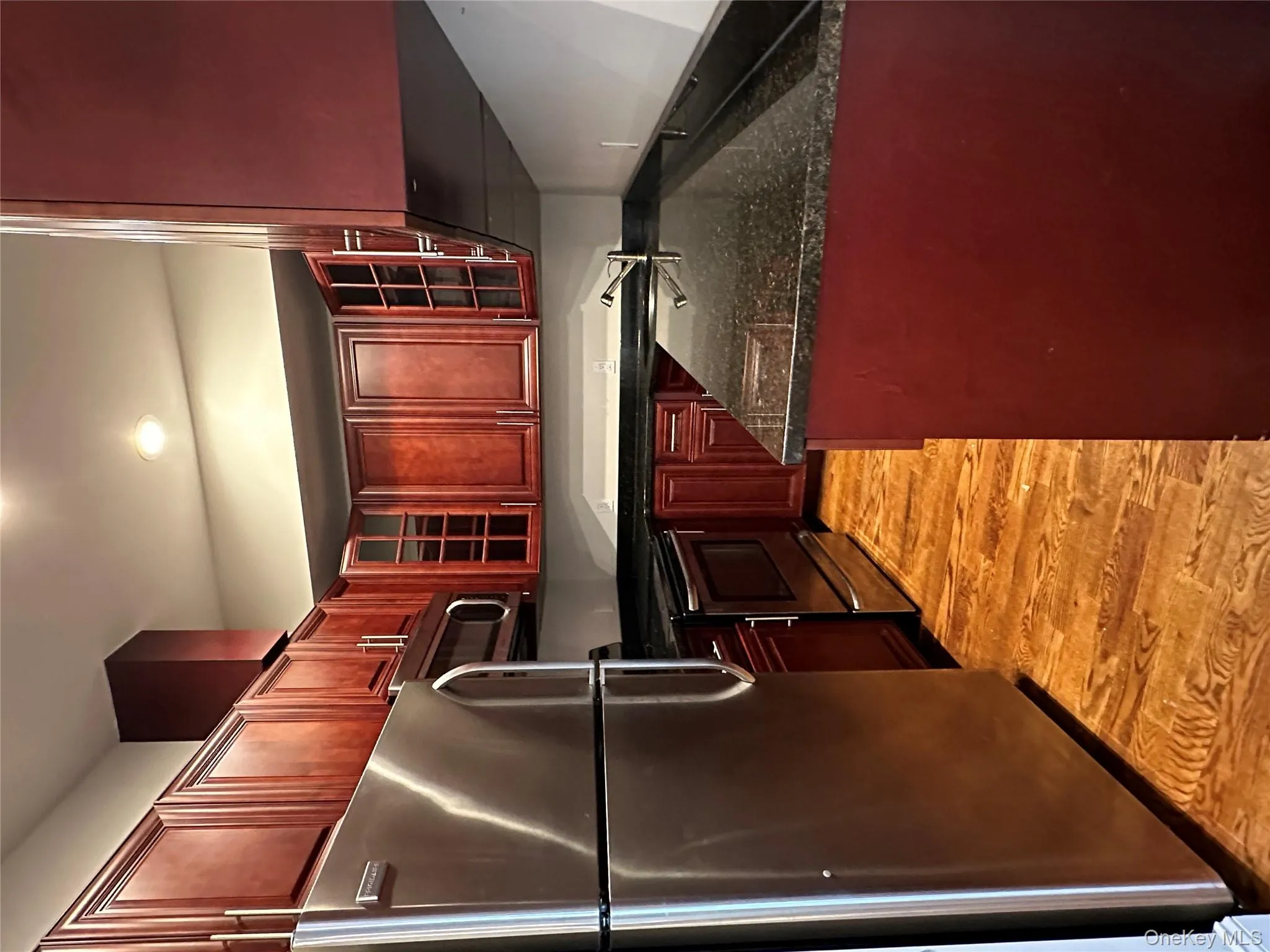 Kitchen featuring dark brown cabinets, appliances with stainless steel finishes, dark stone countertops, glass insert cabinets, and recessed lighting Kitchen featuring dark brown cabinets, appliances with stainless steel finishes, dark stone countertops, glass insert cabinets, and recessed lighting