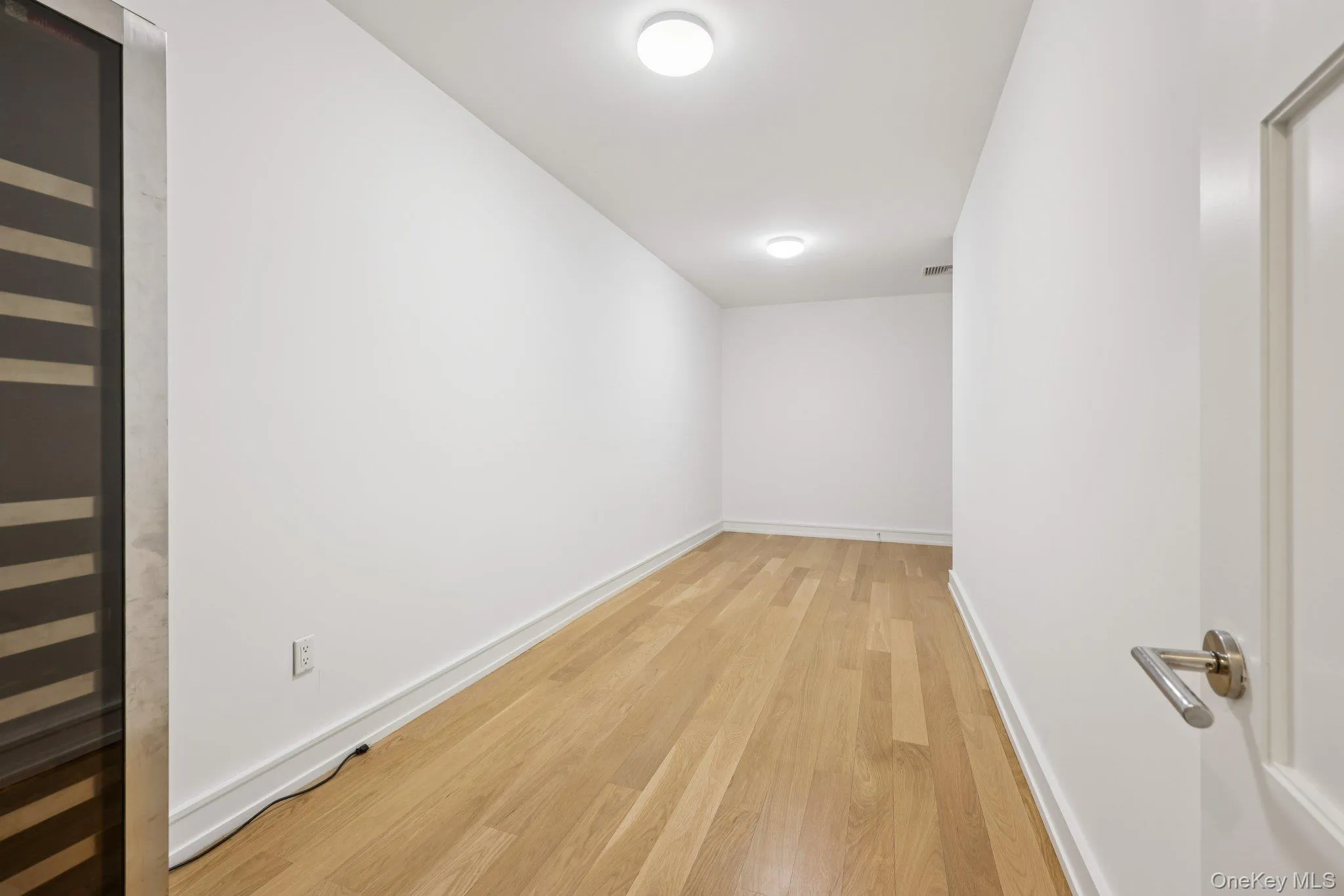 Empty room featuring beverage cooler and light wood finished floors Empty room featuring beverage cooler and light wood finished floors