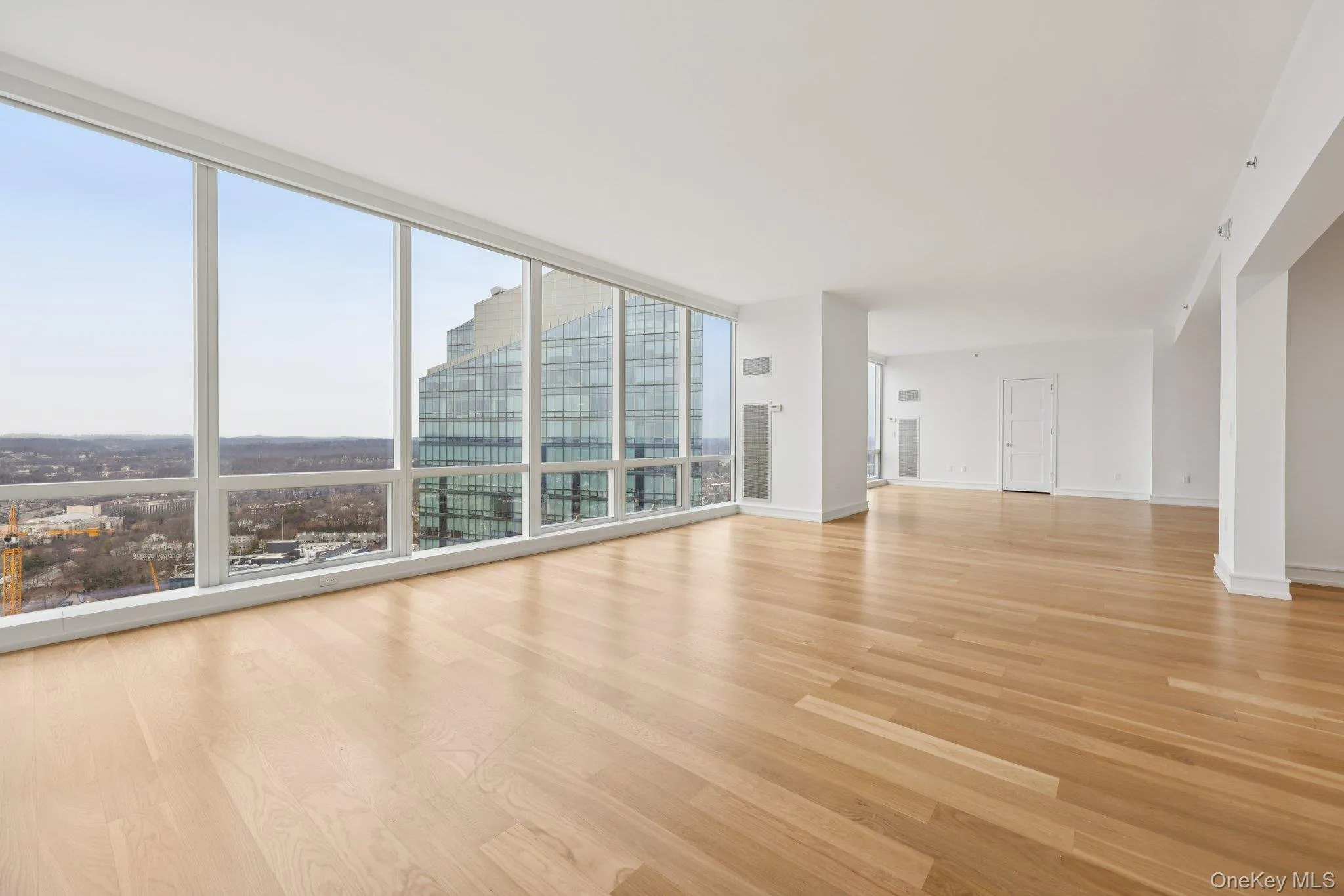 Unfurnished living room with light wood-style flooring, expansive windows, and a city view Unfurnished living room with light wood-style flooring, expansive windows, and a city view