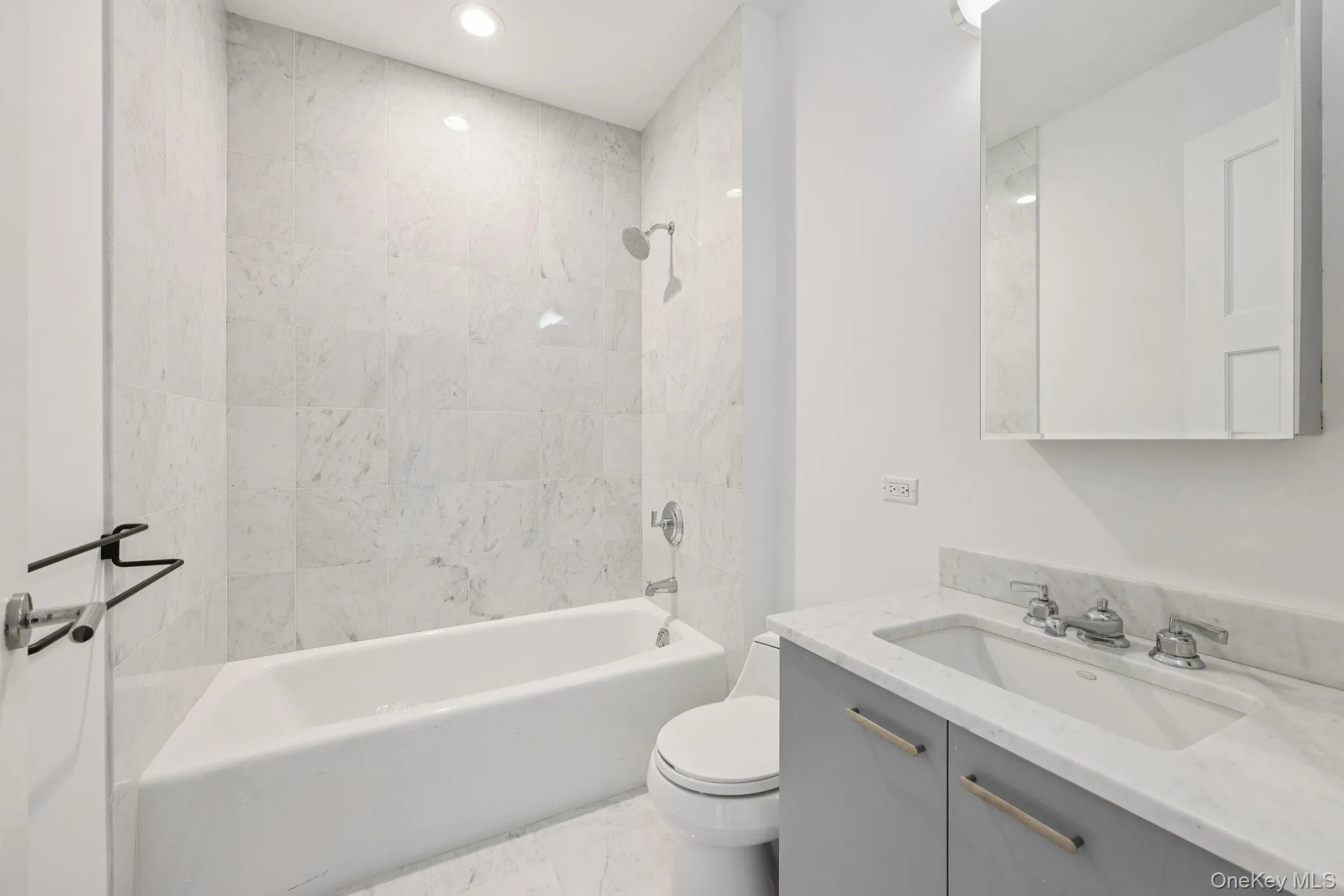 Full bath featuring vanity, shower combination, recessed lighting, and light marble finish floors Full bath featuring vanity, shower combination, recessed lighting, and light marble finish floors