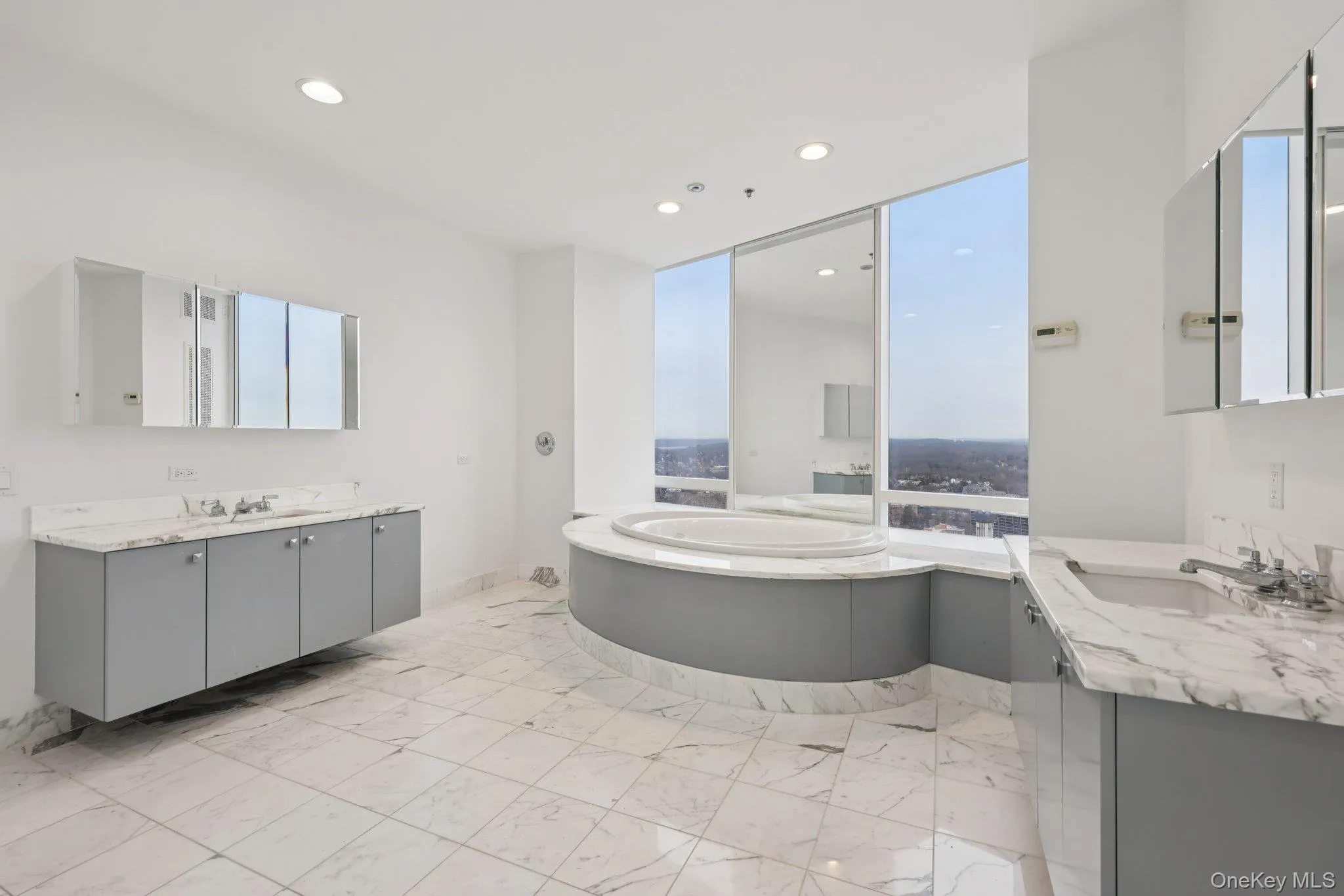 Bathroom featuring two vanities, light marble finish floors, a bath, and recessed lighting Bathroom featuring two vanities, light marble finish floors, a bath, and recessed lighting