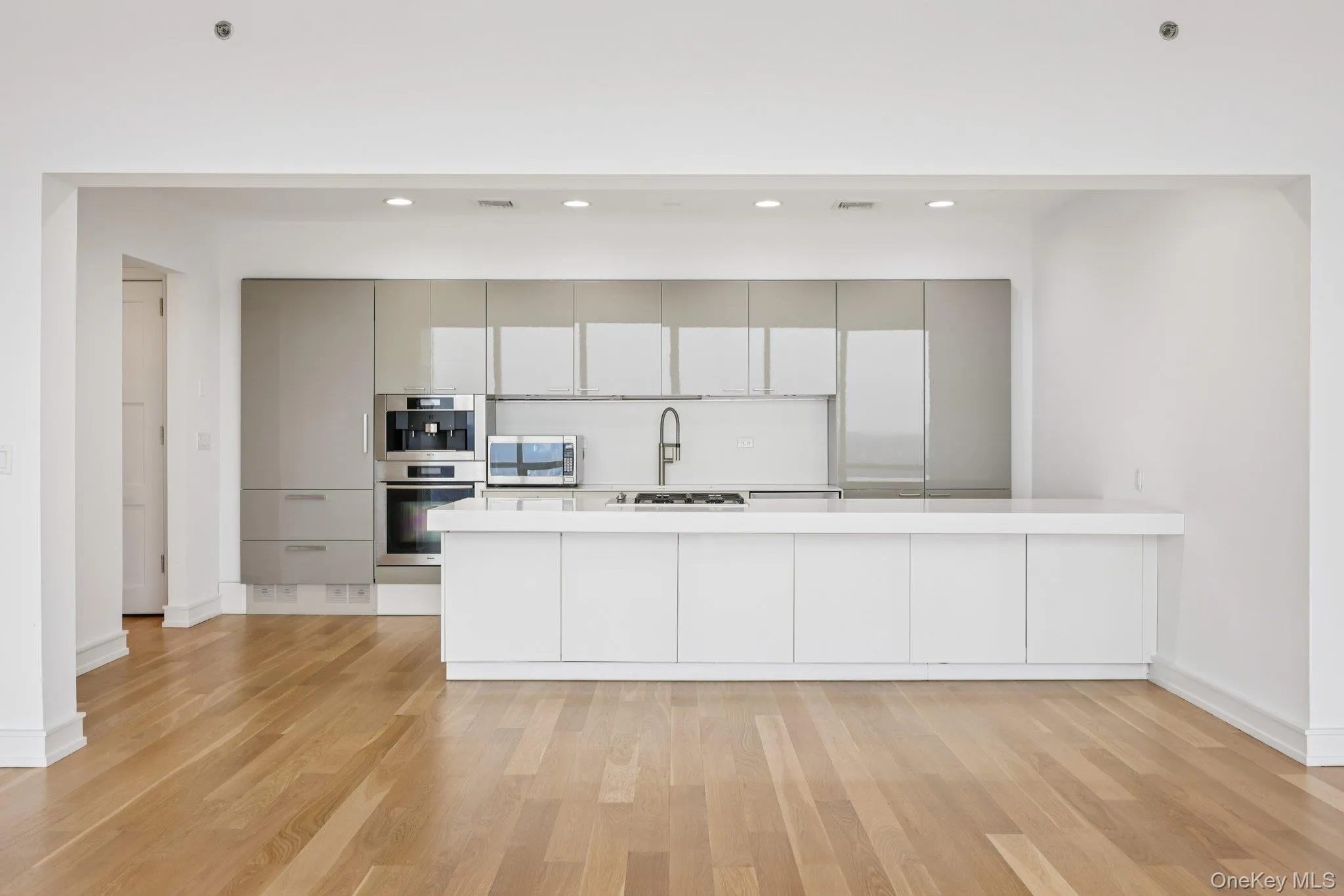Kitchen with a peninsula, modern cabinets, appliances with stainless steel finishes, light wood-style floors, and recessed lighting Kitchen with a peninsula, modern cabinets, appliances with stainless steel finishes, light wood-style floors, and recessed lighting