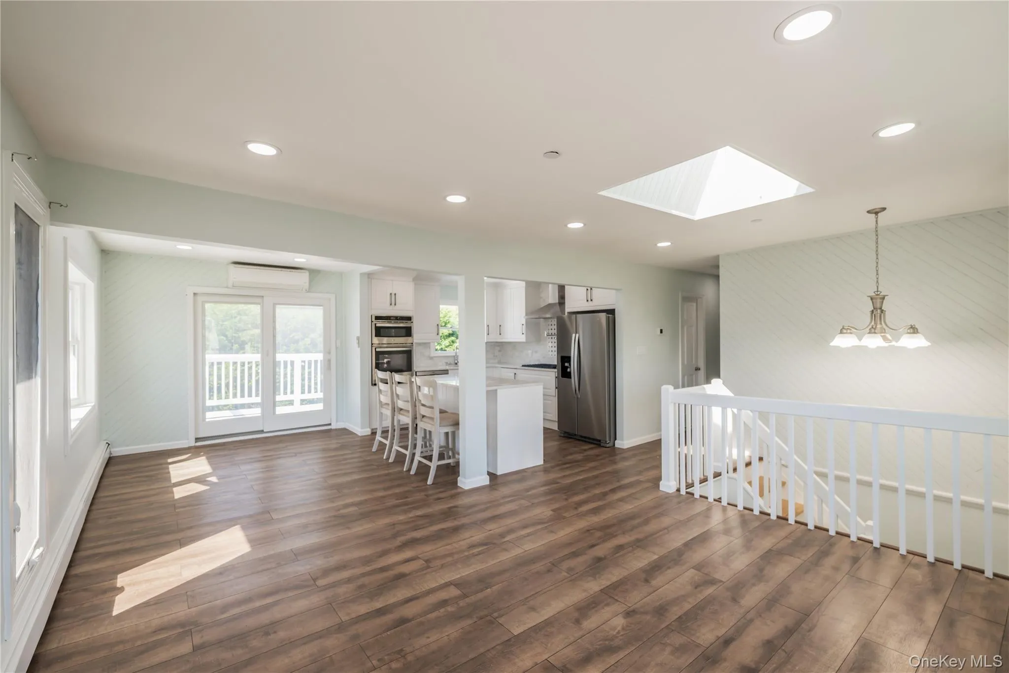 Kitchen with white cabinetry, a skylight, a breakfast bar, hanging light fixtures, and stainless steel appliances Kitchen with white cabinetry, a skylight, a breakfast bar, hanging light fixtures, and stainless steel appliances