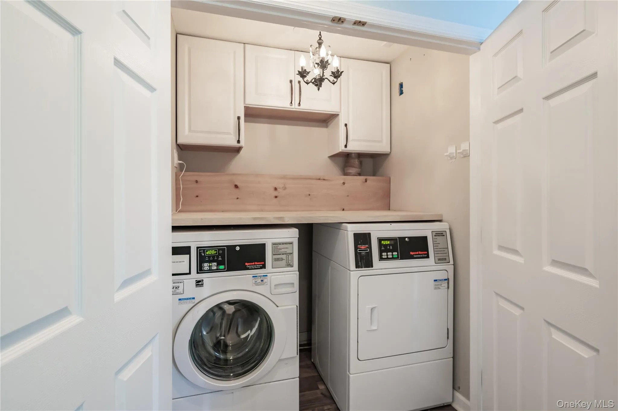 Laundry room with a chandelier, washer and dryer, cabinet space, and dark wood-type flooring Laundry room with a chandelier, washer and dryer, cabinet space, and dark wood-type flooring