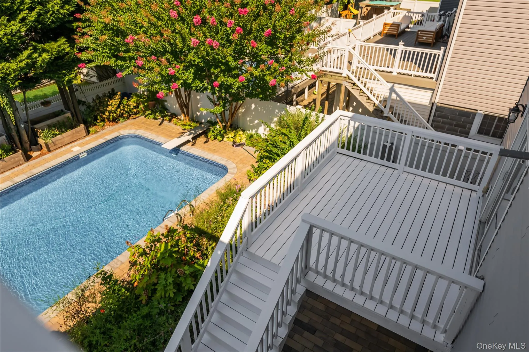 View of swimming pool with stairway, a fenced backyard, and a wooden deck View of swimming pool with stairway, a fenced backyard, and a wooden deck