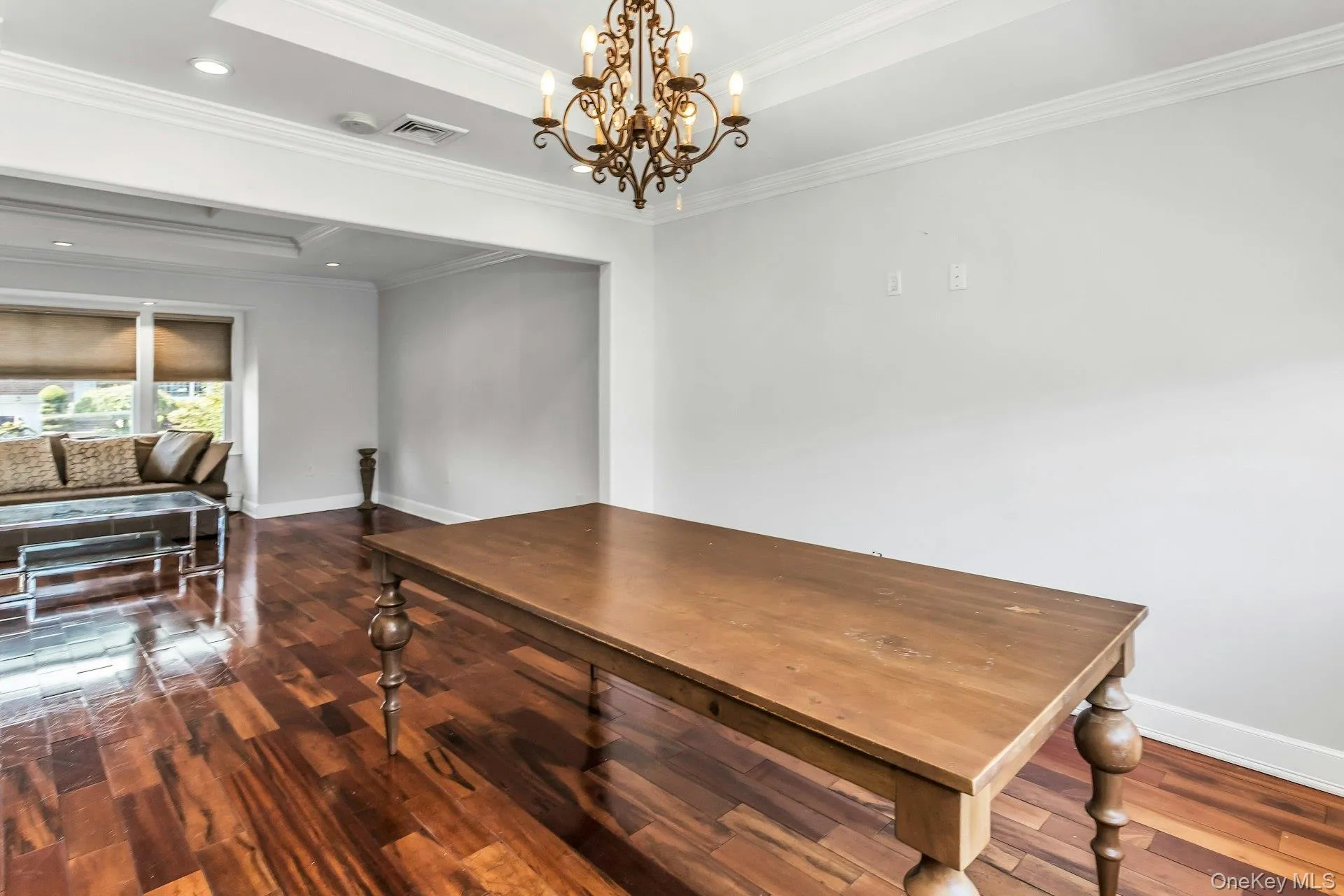Dining space featuring dark wood-type flooring, crown molding, a chandelier, a raised ceiling, and recessed lighting Dining space featuring dark wood-type flooring, crown molding, a chandelier, a raised ceiling, and recessed lighting