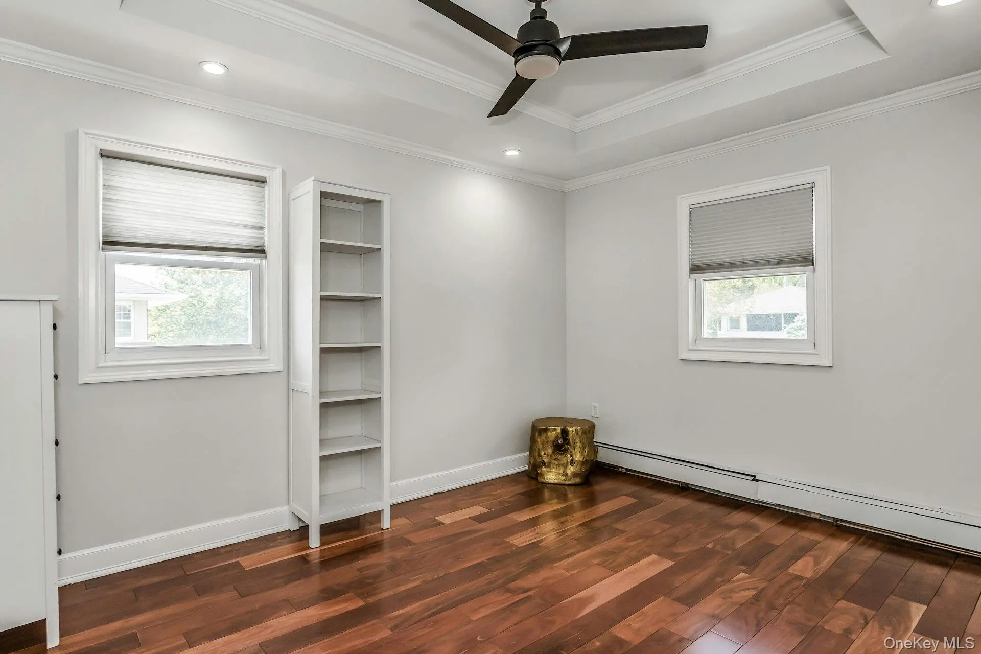 Unfurnished room featuring dark wood-type flooring, a baseboard heating unit, a tray ceiling, recessed lighting, and crown molding Unfurnished room featuring dark wood-type flooring, a baseboard heating unit, a tray ceiling, recessed lighting, and crown molding