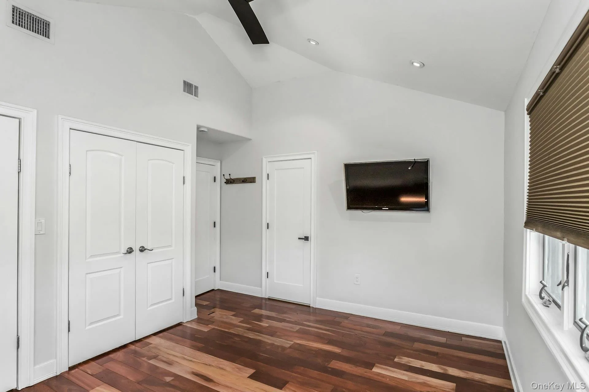 Unfurnished bedroom with dark wood finished floors and high vaulted ceiling Unfurnished bedroom with dark wood finished floors and high vaulted ceiling
