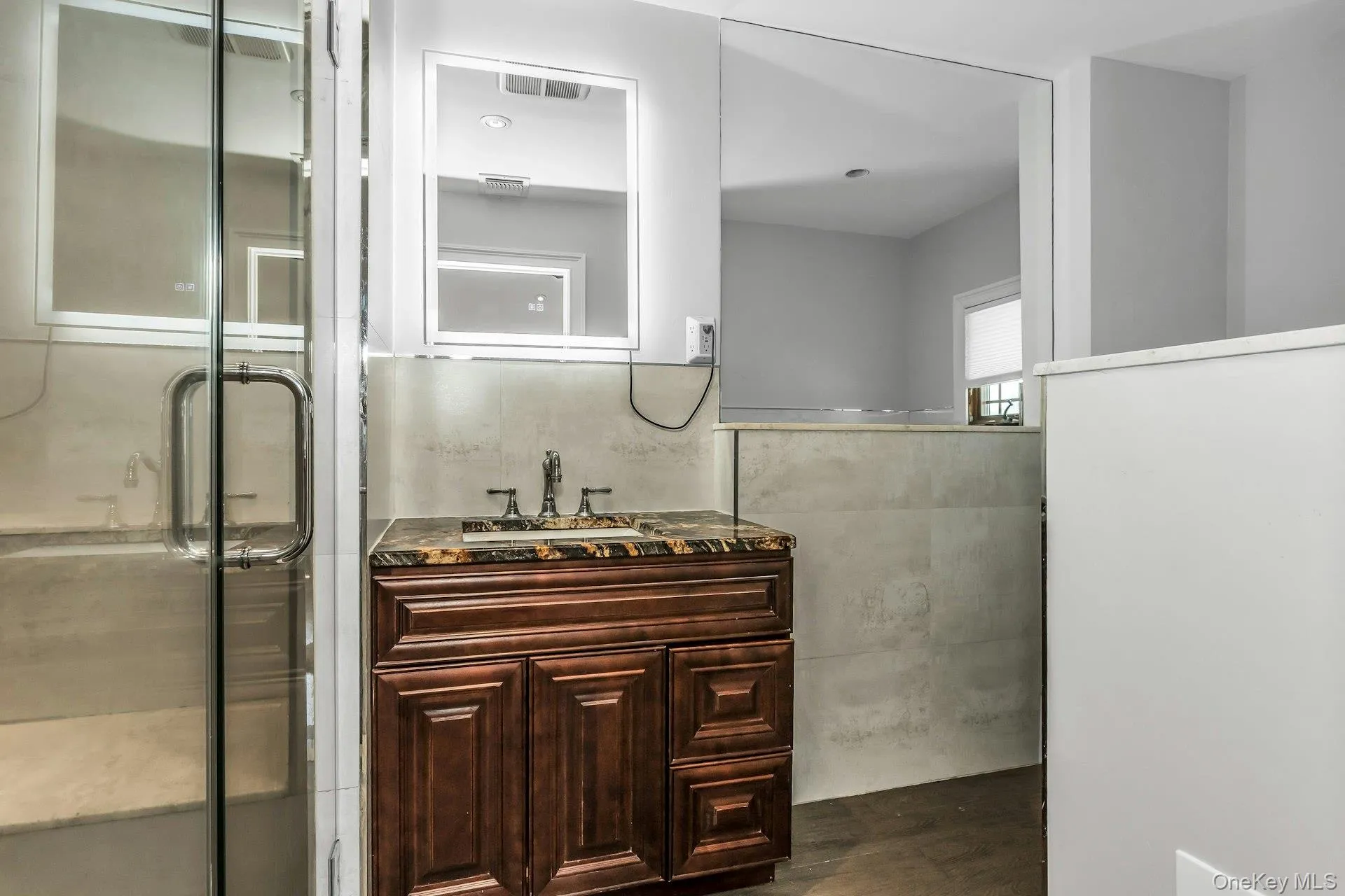 Bathroom with vanity, a stall shower, tile walls, dark wood finished floors, and wainscoting Bathroom with vanity, a stall shower, tile walls, dark wood finished floors, and wainscoting