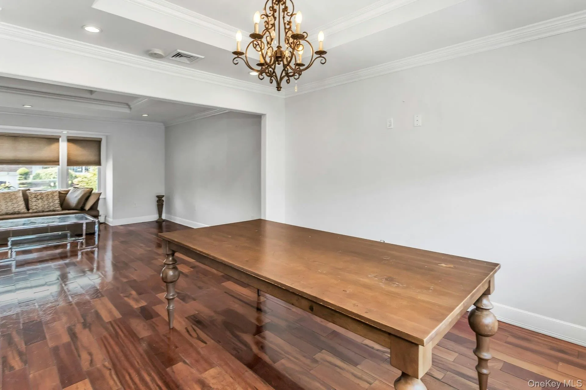 Dining room with dark wood-style floors, ornamental molding, a raised ceiling, a chandelier, and recessed lighting Dining room with dark wood-style floors, ornamental molding, a raised ceiling, a chandelier, and recessed lighting