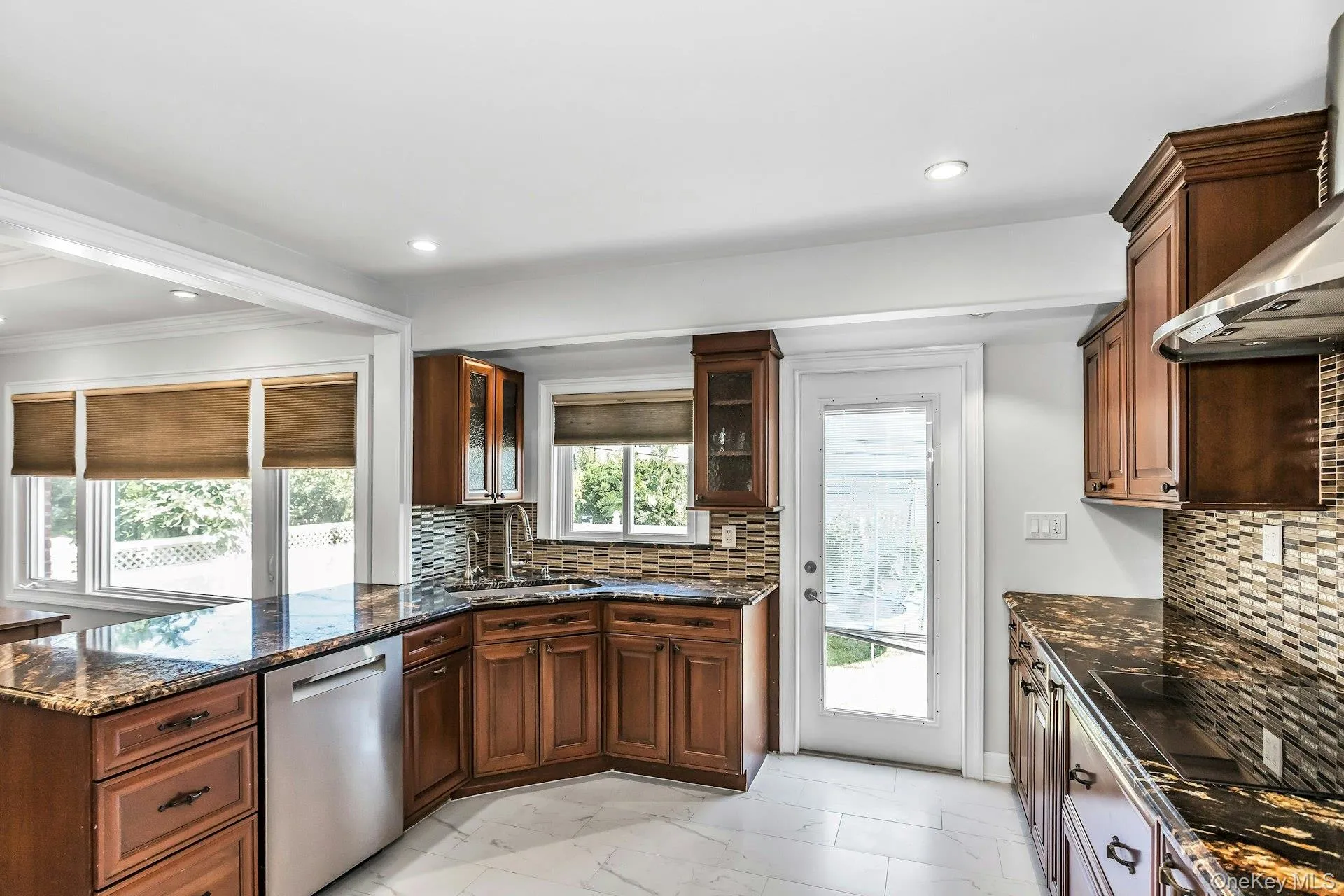 Kitchen featuring tasteful backsplash, dark stone countertops, dishwasher, light marble finish flooring, and recessed lighting Kitchen featuring tasteful backsplash, dark stone countertops, dishwasher, light marble finish flooring, and recessed lighting