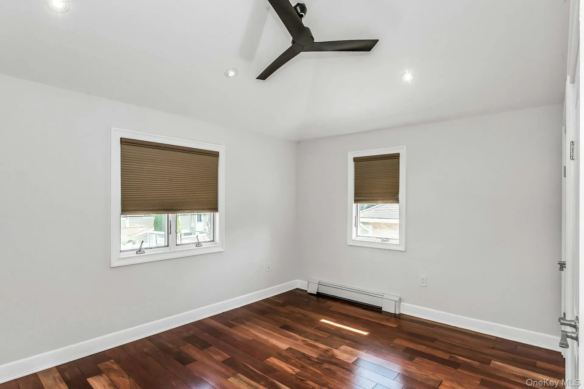 Empty room with a baseboard heating unit, dark wood finished floors, recessed lighting, and a ceiling fan Empty room with a baseboard heating unit, dark wood finished floors, recessed lighting, and a ceiling fan