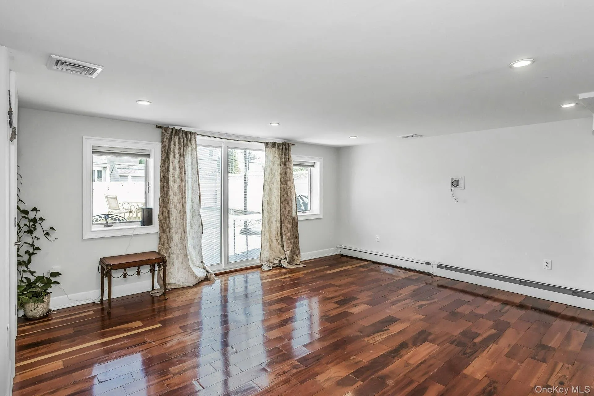 Unfurnished room with dark wood finished floors, a baseboard heating unit, and recessed lighting Unfurnished room with dark wood finished floors, a baseboard heating unit, and recessed lighting